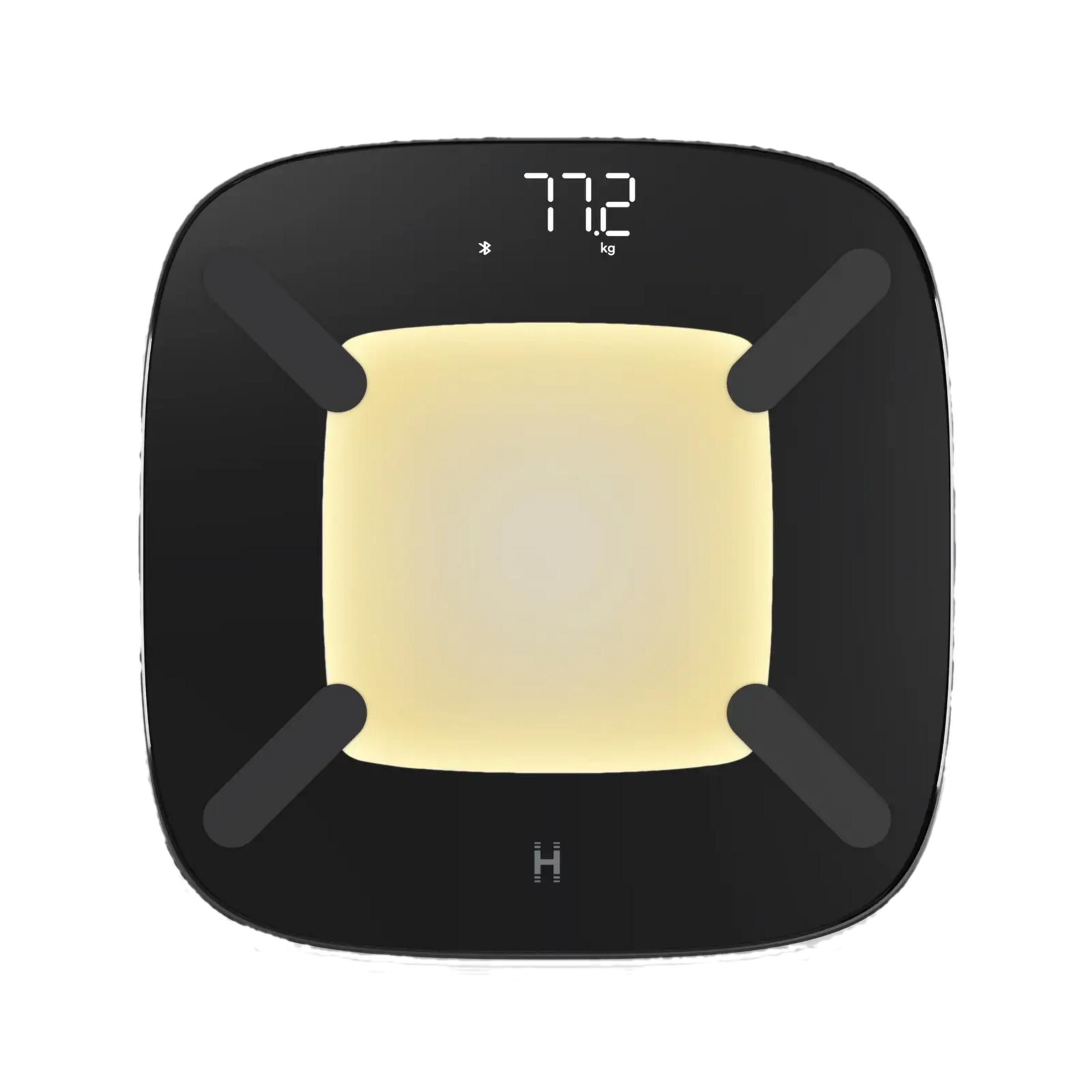 Czarna waga cyfrowa pokazuje 77.2 kg, z podświetlanym panelem i symbolem Bluetooth.