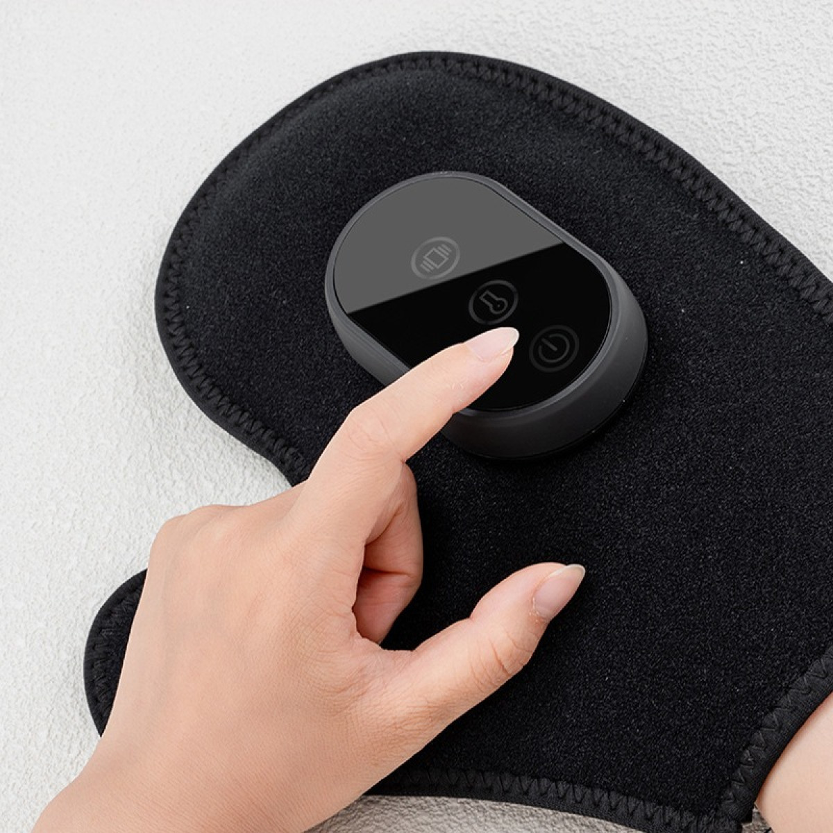 Dłoń naciska czarny przycisk sterowania na czarnej opasce.