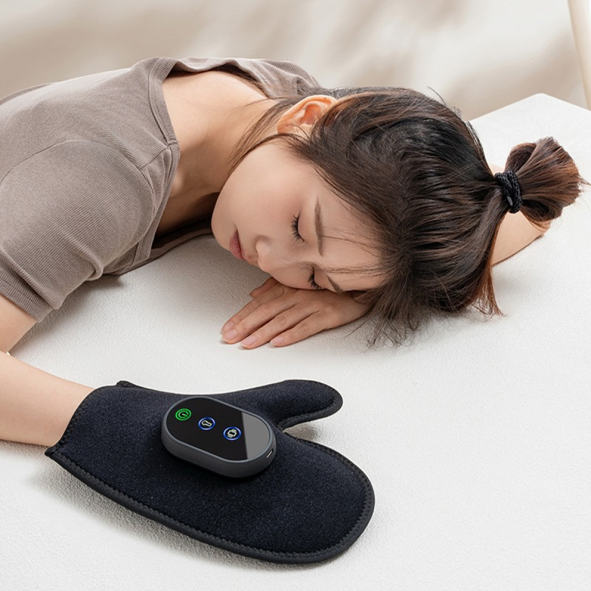 Kobieta z zamkniętymi oczami leży na białej powierzchni. Ma na sobie szare ubranie i czarną rękawicę.