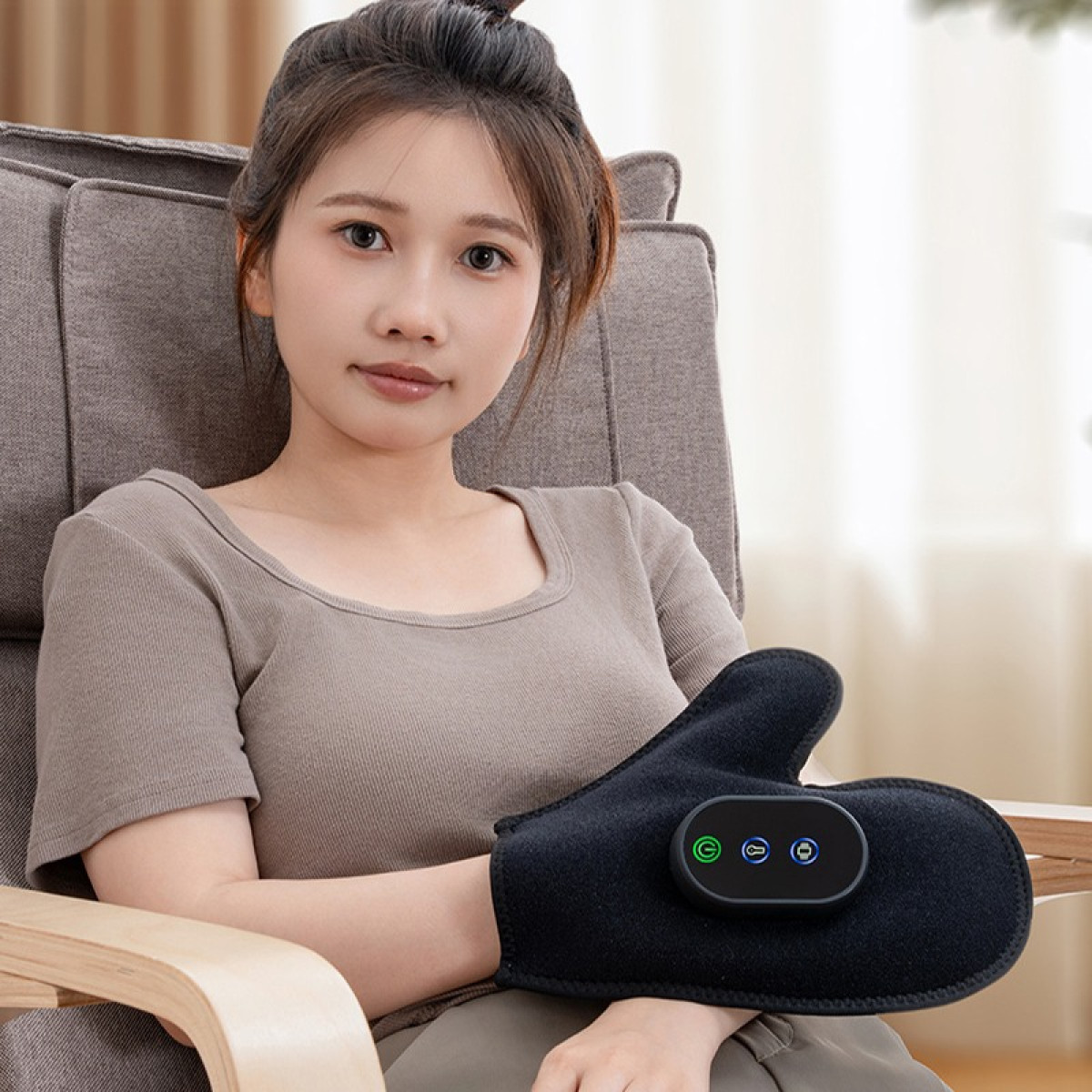 Kobieta siedzi na krześle w czarnej rękawicy do masażu dłoni.