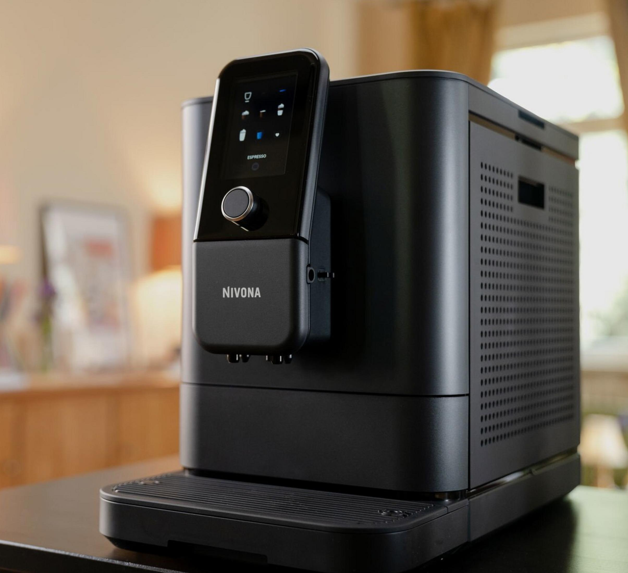 Macchina da caffè nera con touchscreen e manopola su un tavolo.