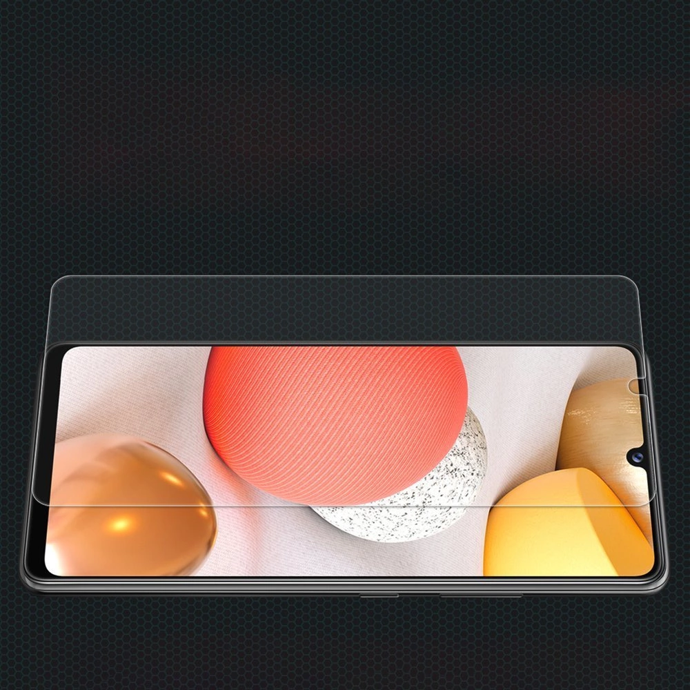 Schermo smartphone con pellicola protettiva, mostra forme astratte arancioni, dorate e grigie.