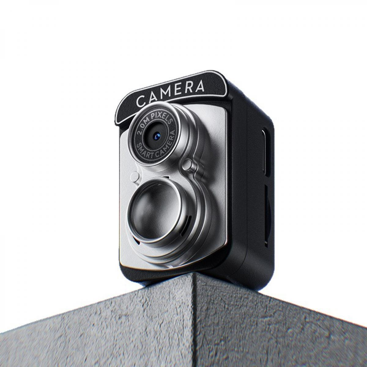 Eine kleine silberne und schwarze Kamera mit der Aufschrift "CAMERA" sitzt auf einer grauen Oberfläche.