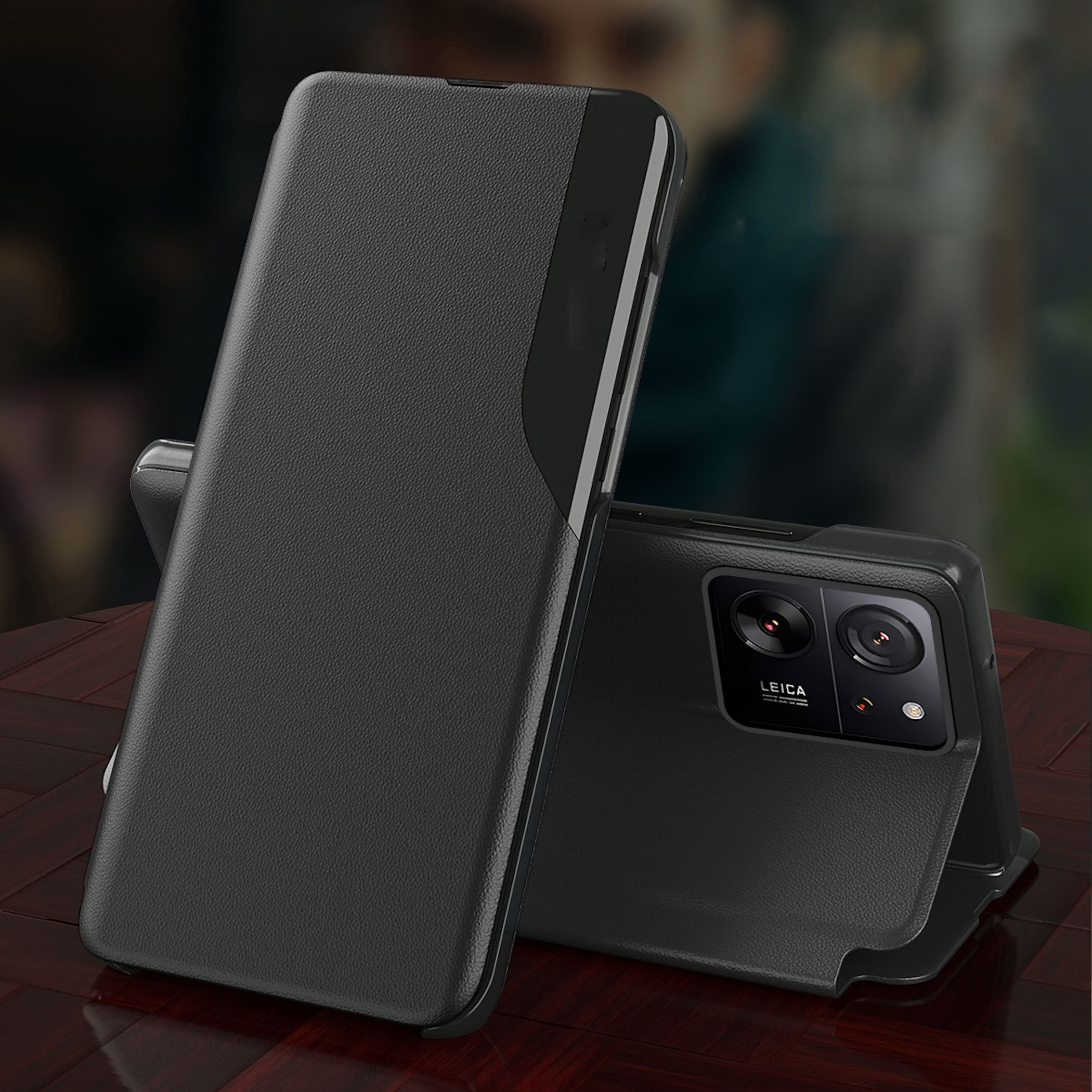 Schwarzes Handy mit einer Klapphülle auf einem Holztisch.