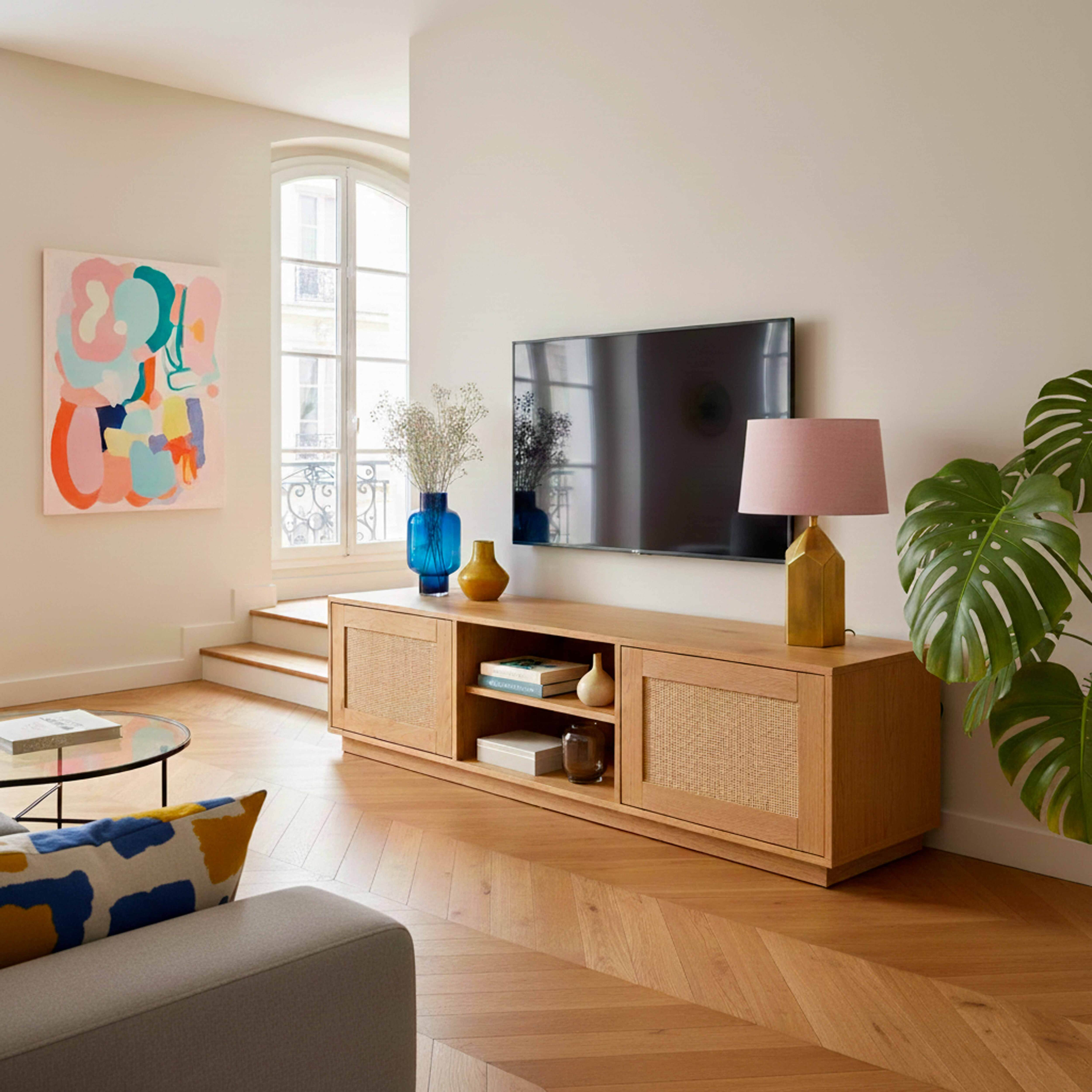 Ein Wohnzimmer mit Holzmöbeln, einem Fernseher, einer Lampe und Kunst.