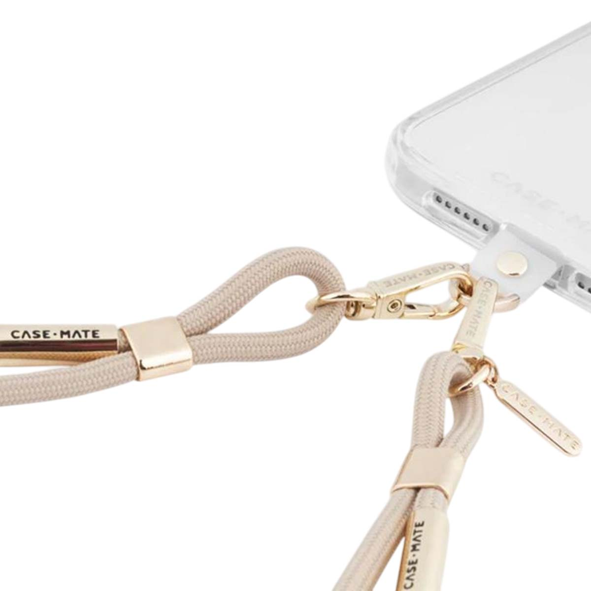 Nahaufnahme einer cremefarbenen Handy-Schlaufe, die mit goldener Hardware an einer Hülle befestigt ist.