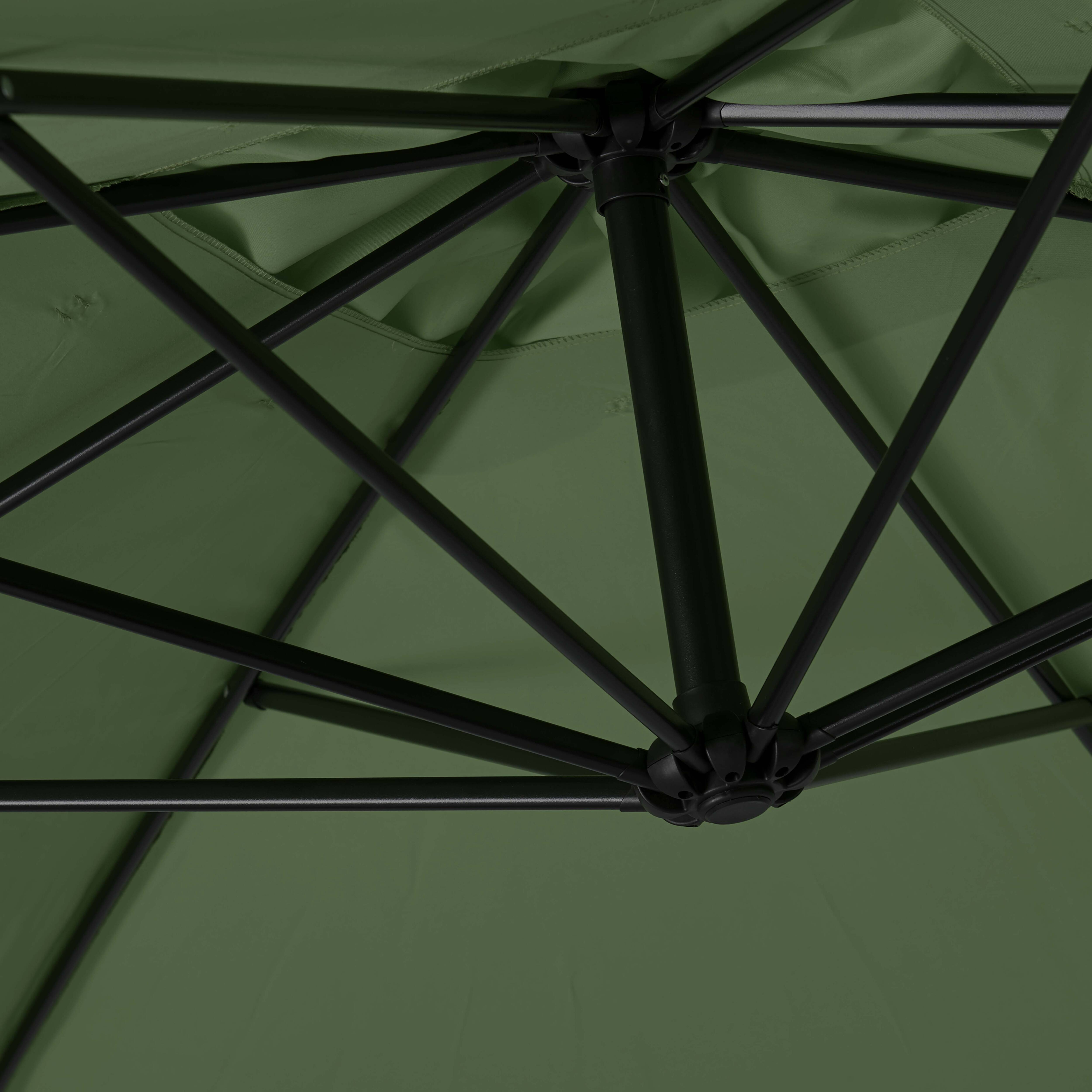 Grüner Sonnenschirmstoff mit schwarzem Metallrahmen von unten gesehen.