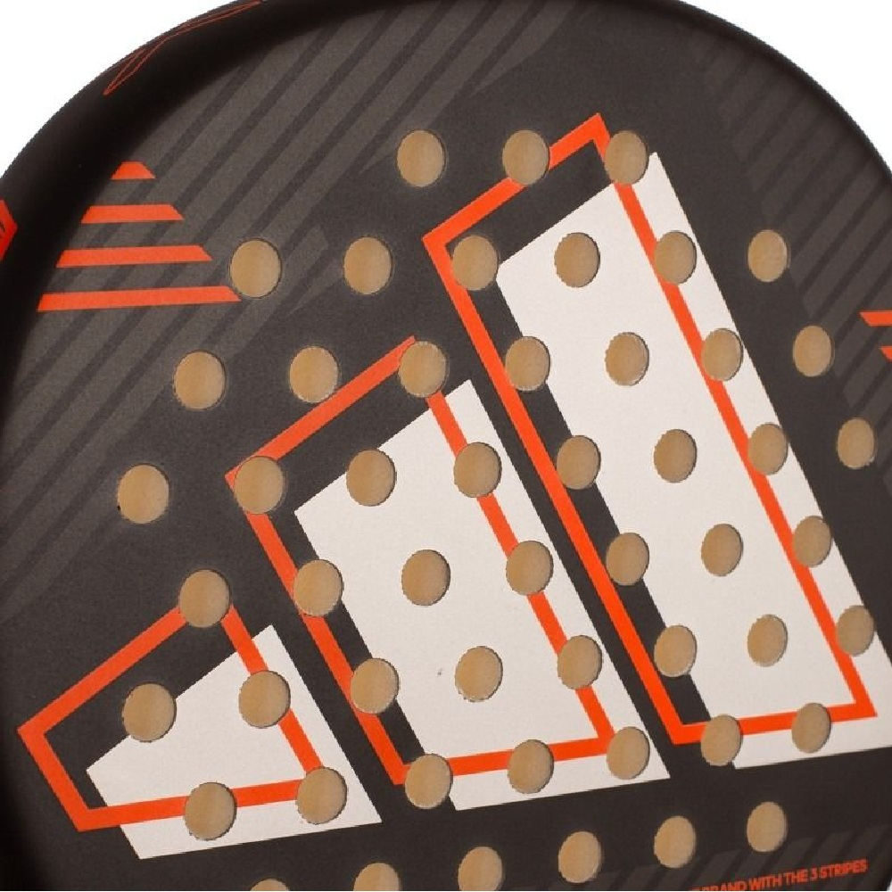 Primer plano de una pala de pádel negra con logo Adidas blanco y naranja y muchos agujeros.