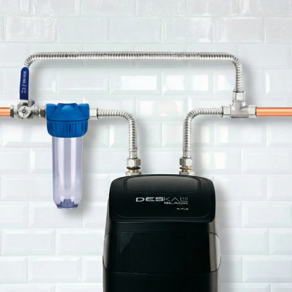Un filtro de agua negro con tapa azul y recipiente transparente montado.