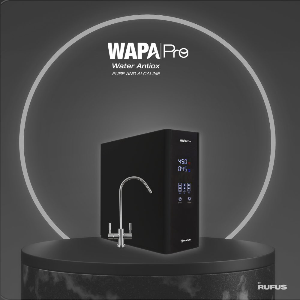 Filtro de agua negro con grifo plateado sobre pedestal oscuro.