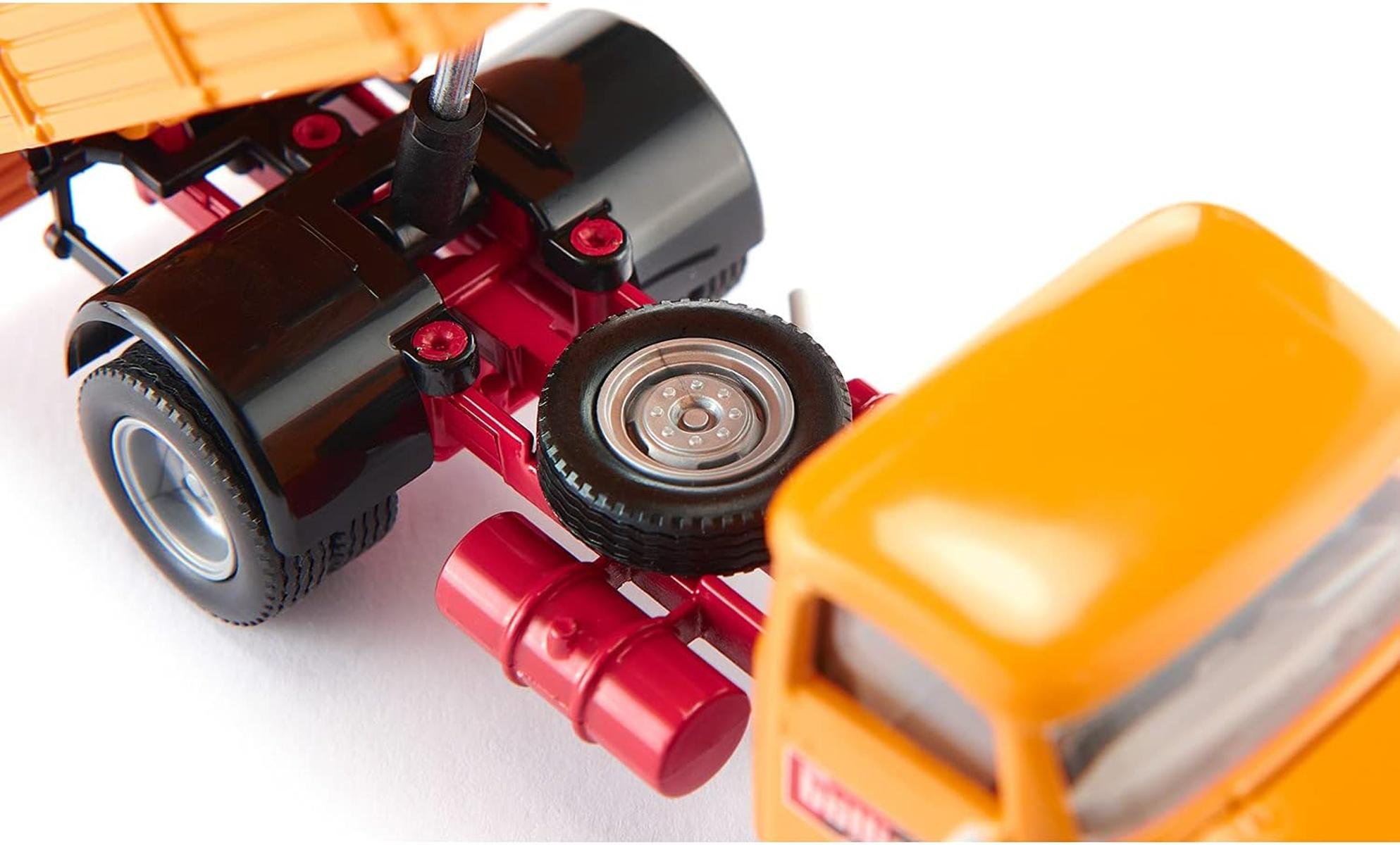 Detailaufnahme eines gelben Spielzeuglastwagens mit rotem Fahrgestell und schwarzen Radkästen.