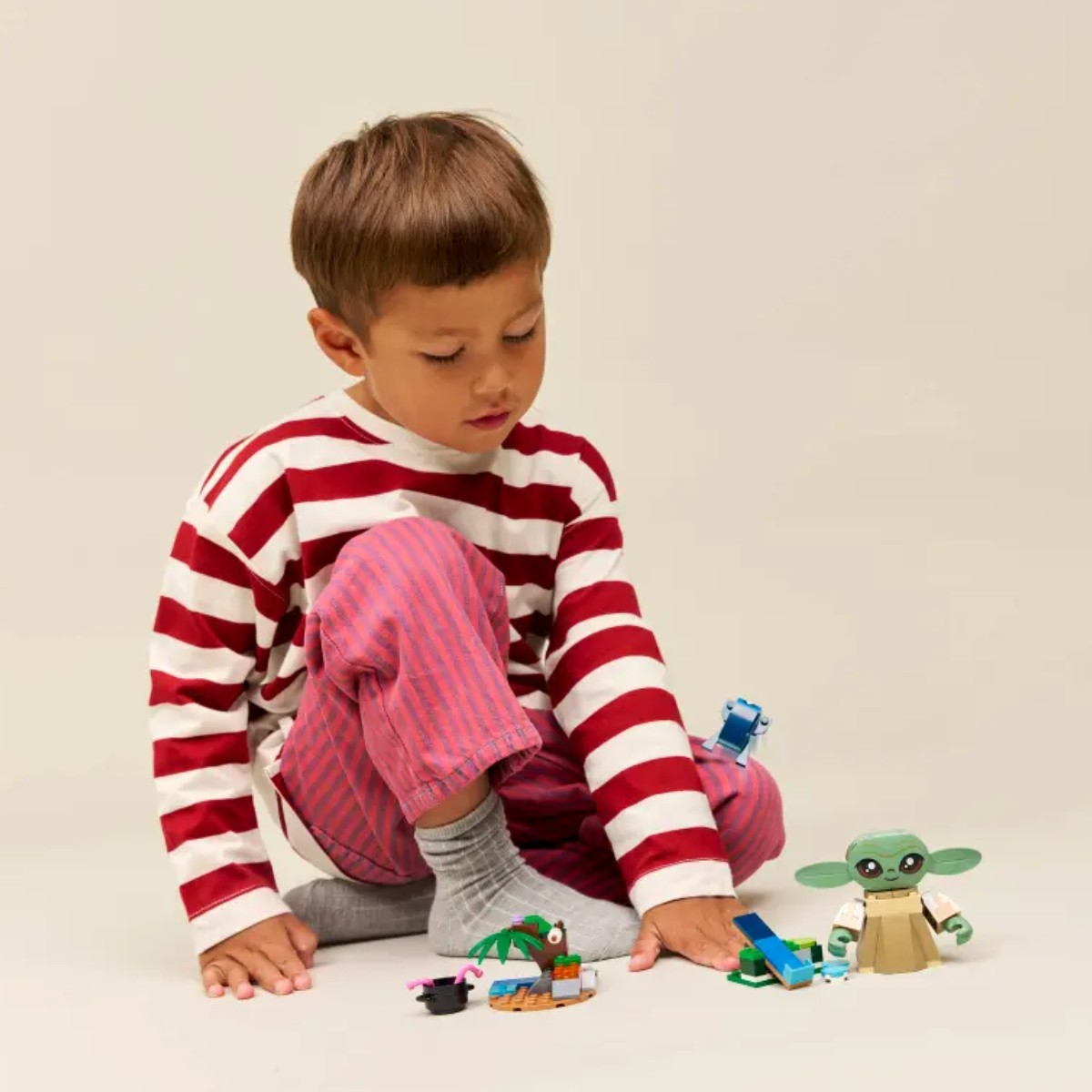 Chłopiec bawi się figurkami Lego, w tym Baby Yodą i małą scenką z wyspą.