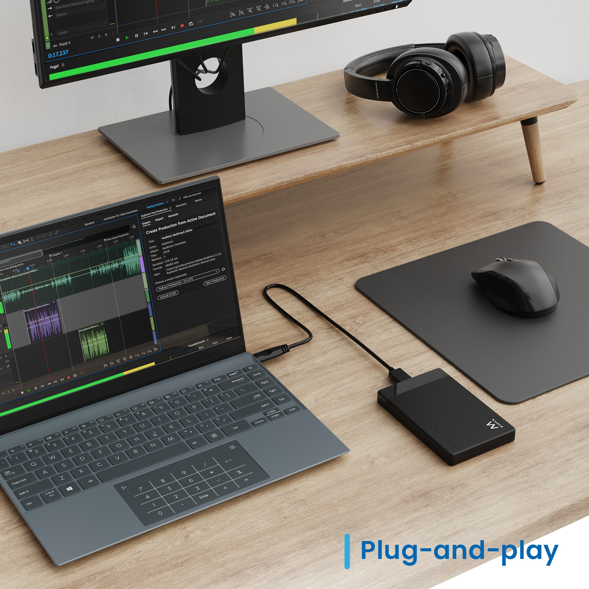 Un laptop con software audio, hard disk esterno, mouse e cuffie su una scrivania di legno.