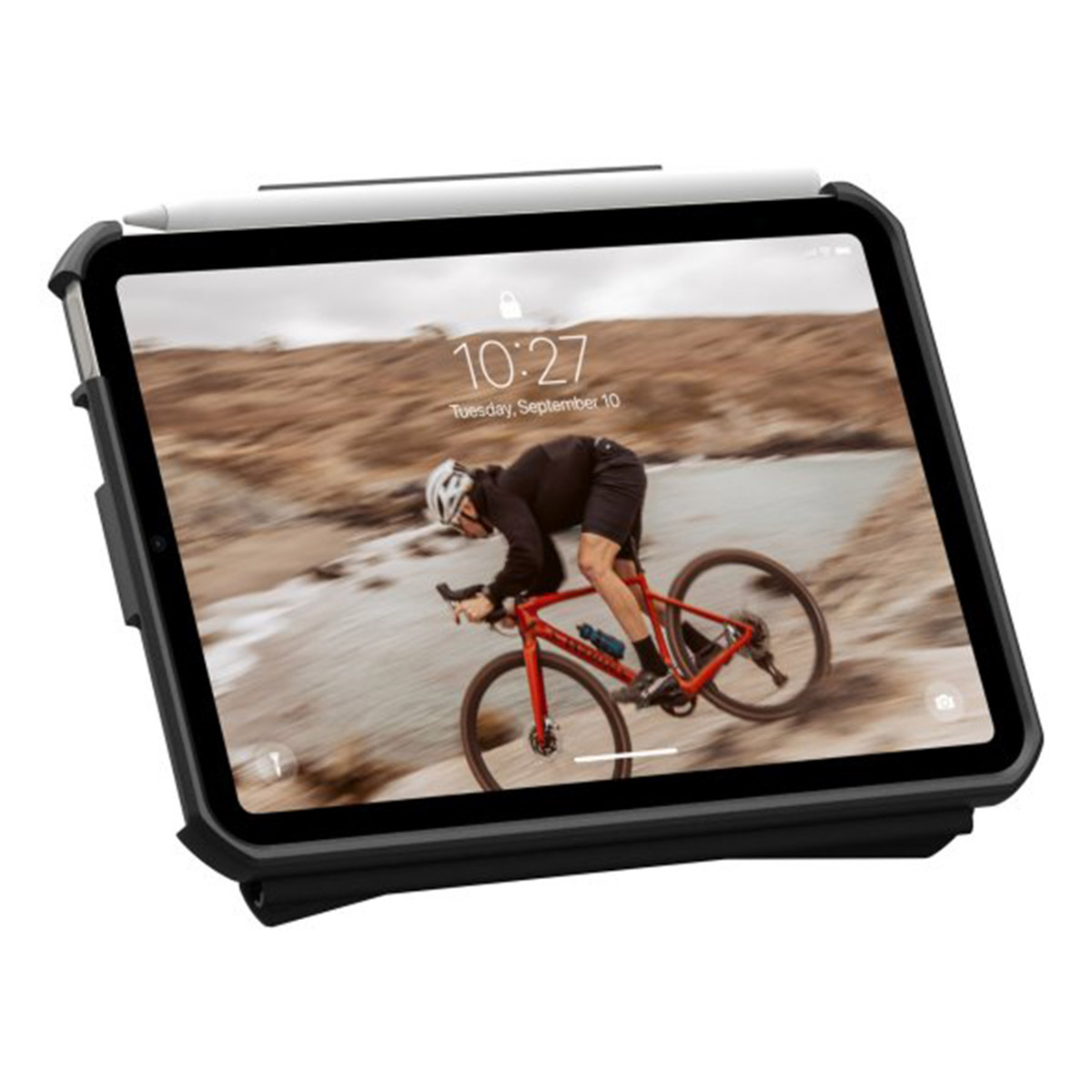 Tablet met stylus toont fietser op rode fiets; rotsachtige, wazige achtergrond.