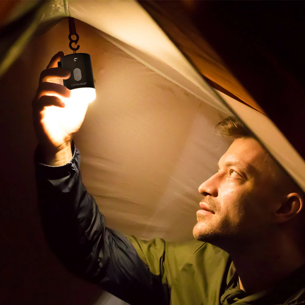 Mann hält eine leuchtende Campinglaterne in einem Zelt.
