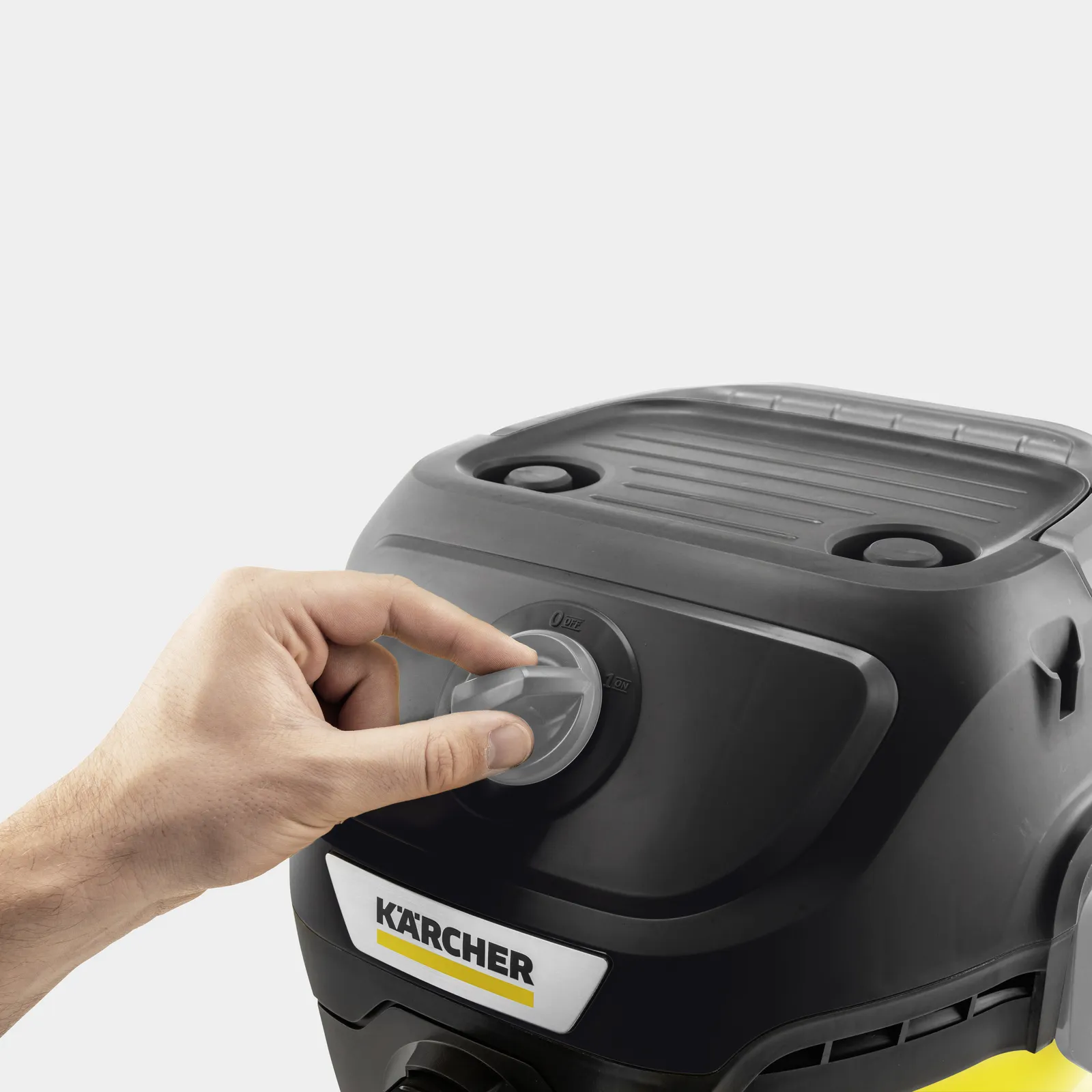 A hand turns a dial on a black Karcher device from OFF to ON.