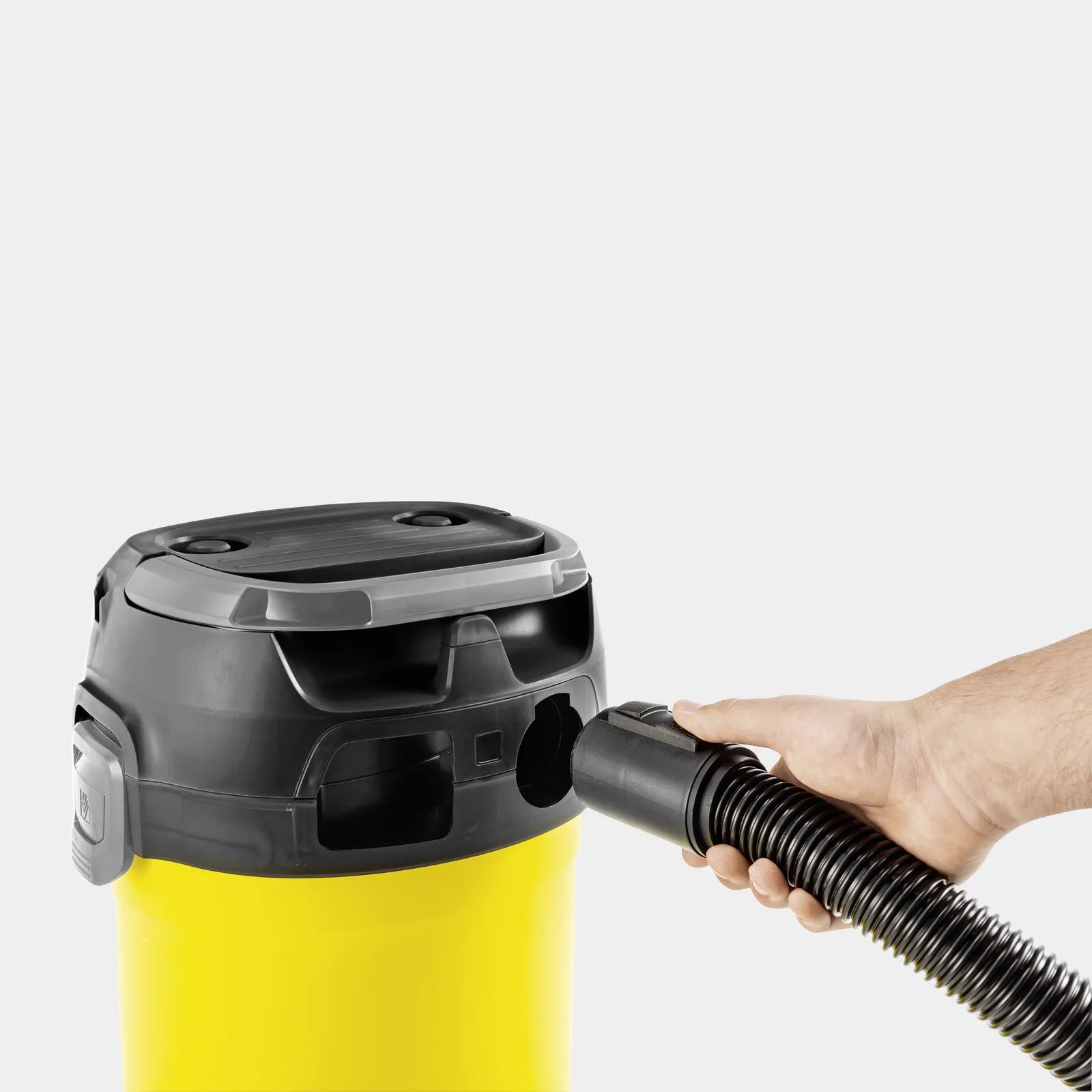 Hand inserts hose into yellow wet/dry vacuum cleaner.