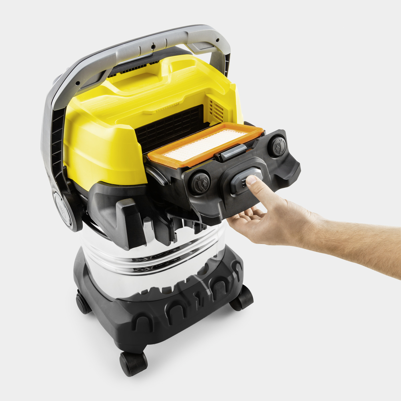 A man removes a filter from a yellow and black vacuum cleaner.