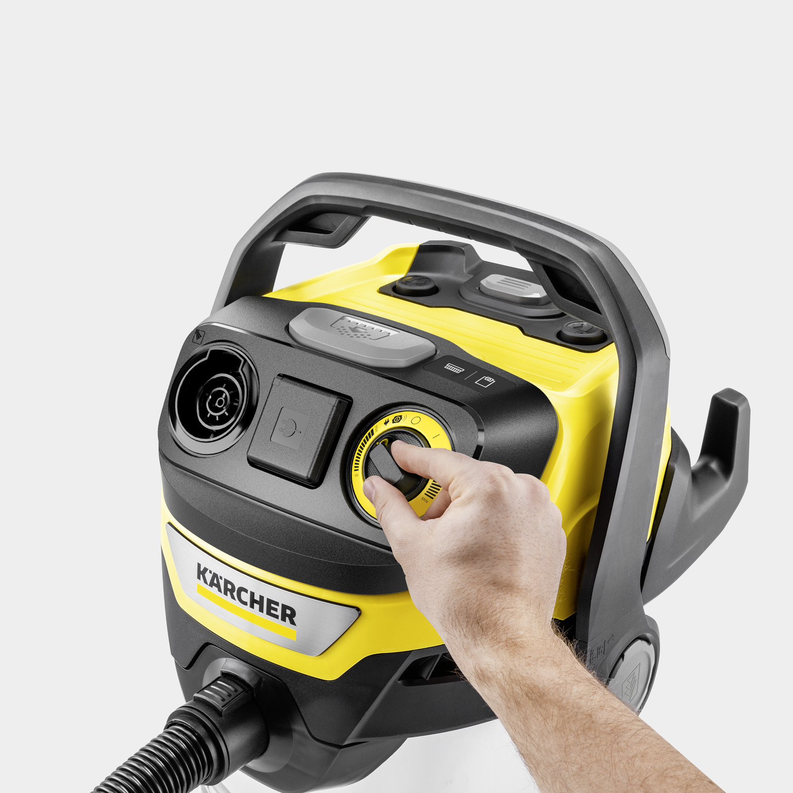 Hand turning yellow dial on Karcher vacuum cleaner with hose connection.