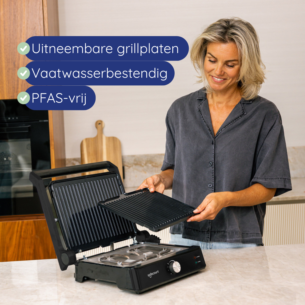 A woman holds a grill plate of an open contact grill machine.