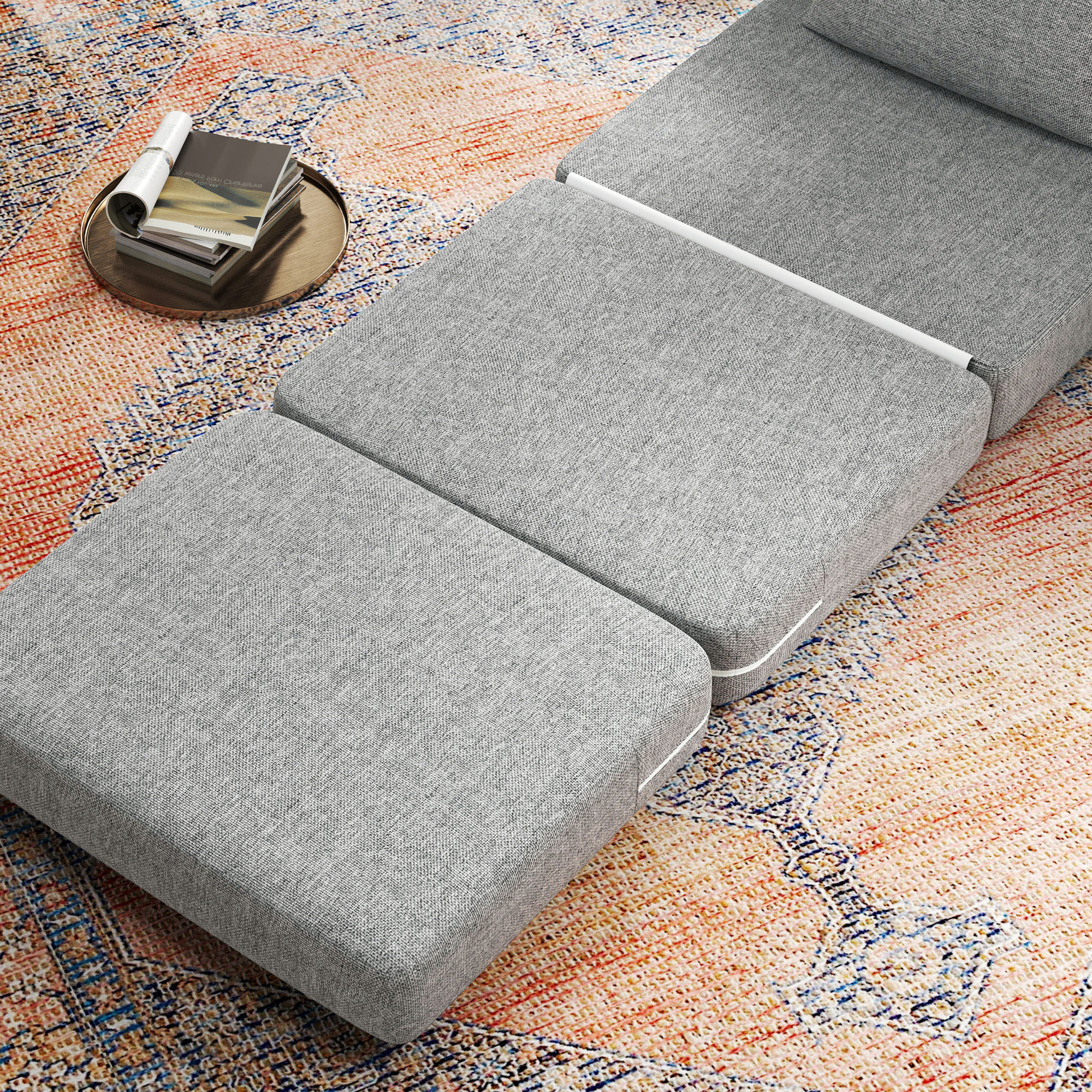 Divano grigio con pouf su tappeto fantasia. Libri su un vassoio.