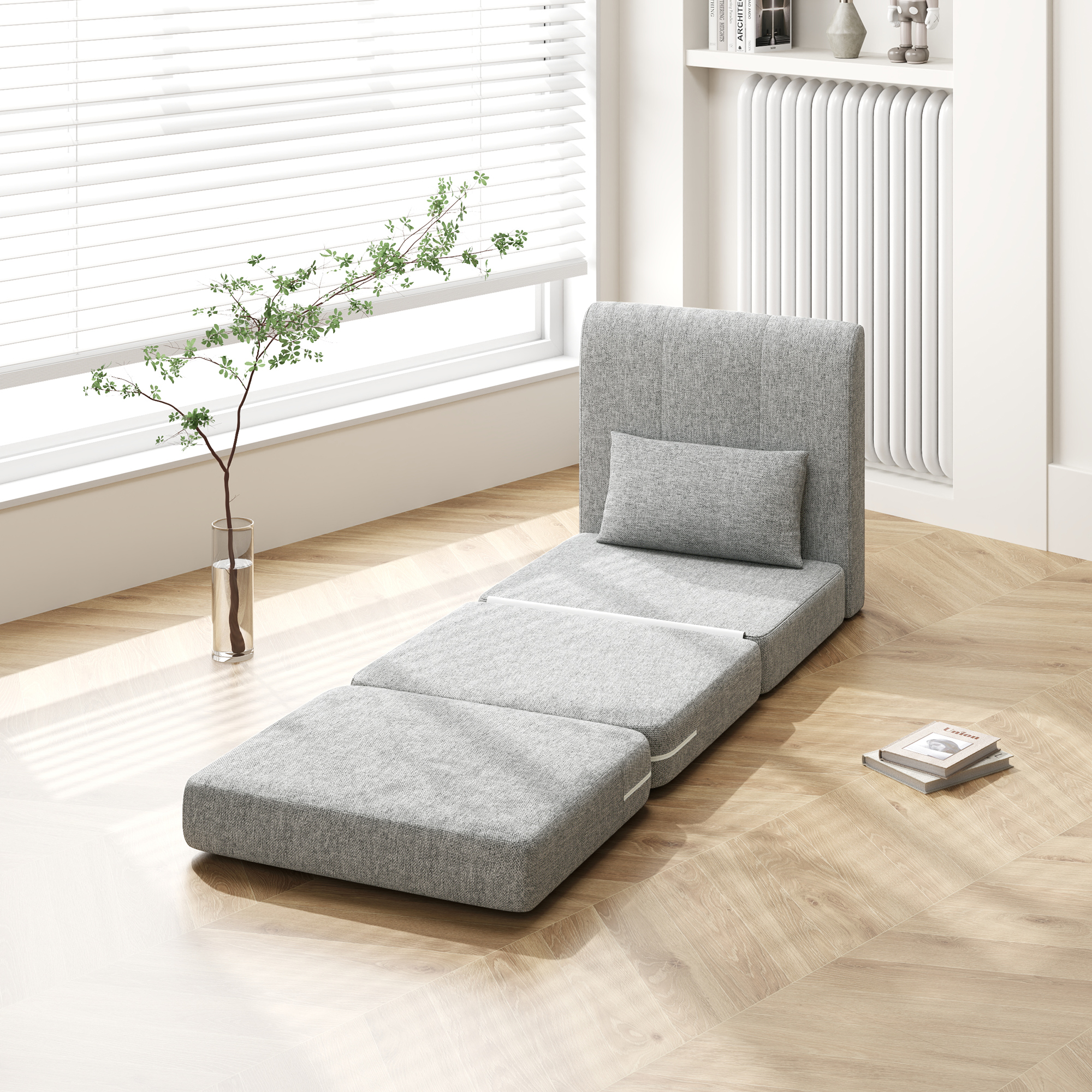 Un divano modulare grigio si apre in letto su pavimento in legno vicino a finestra con persiane.