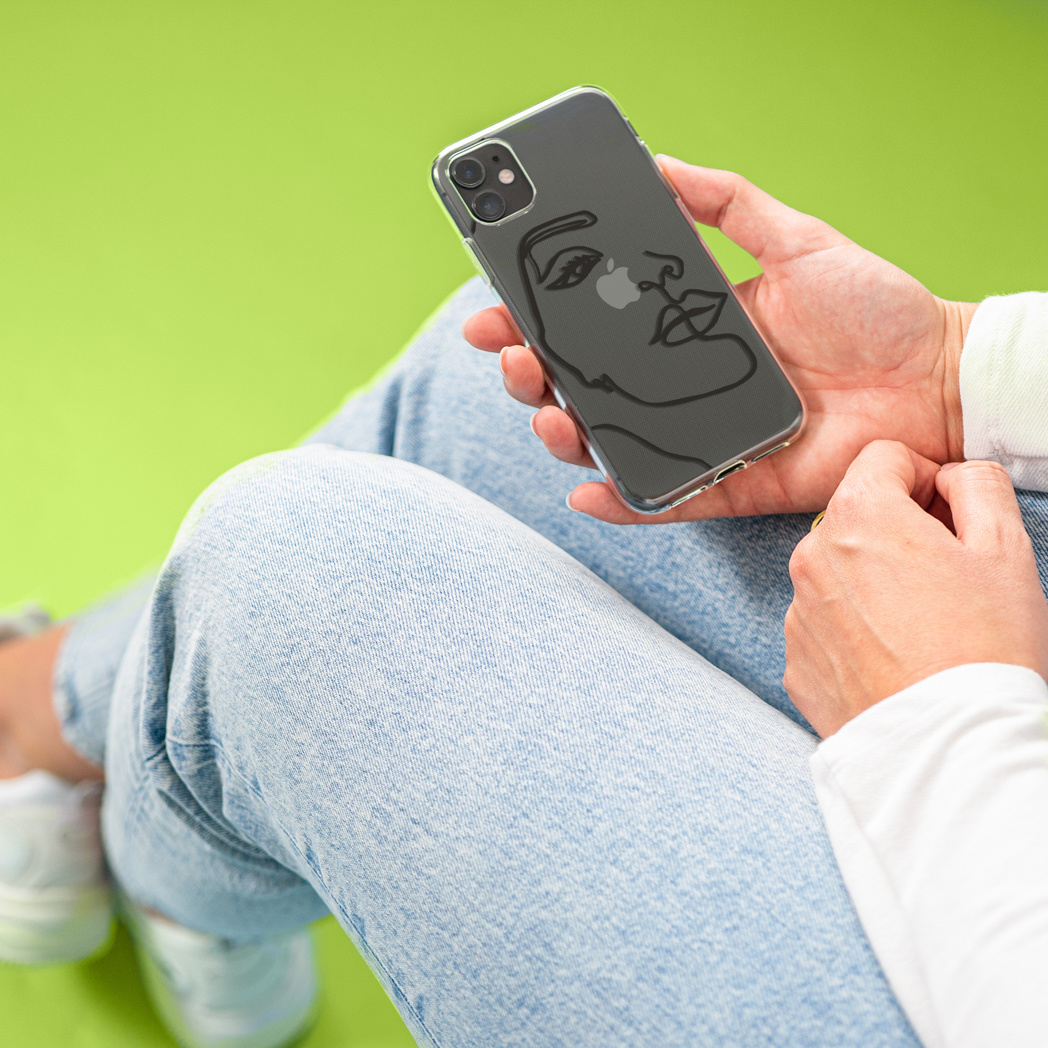 Personne tenant un téléphone avec un contour de visage abstrait sur une coque transparente.