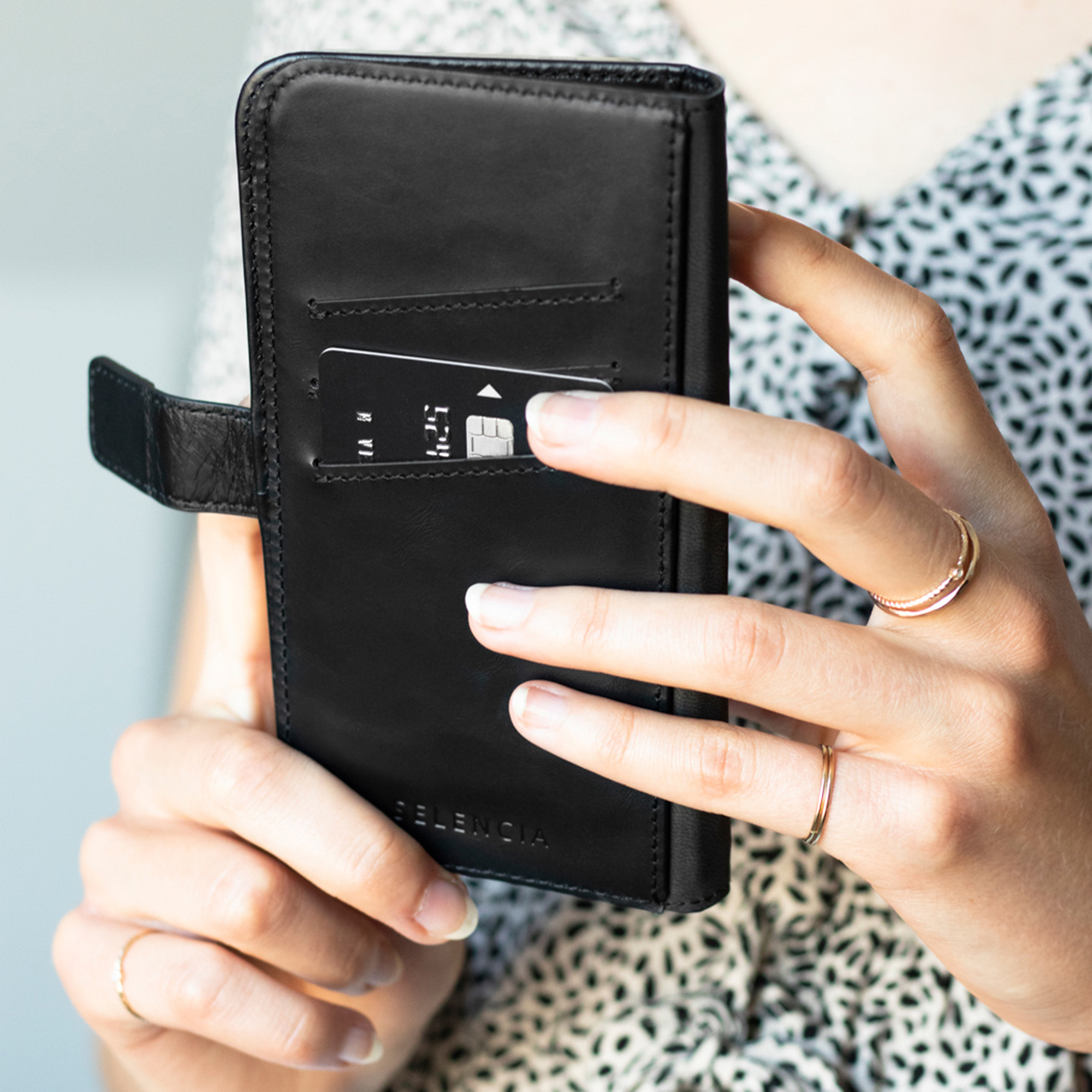 Een hand houdt een zwarte portemonnee vast met een creditcard die in een sleuf wordt geschoven.