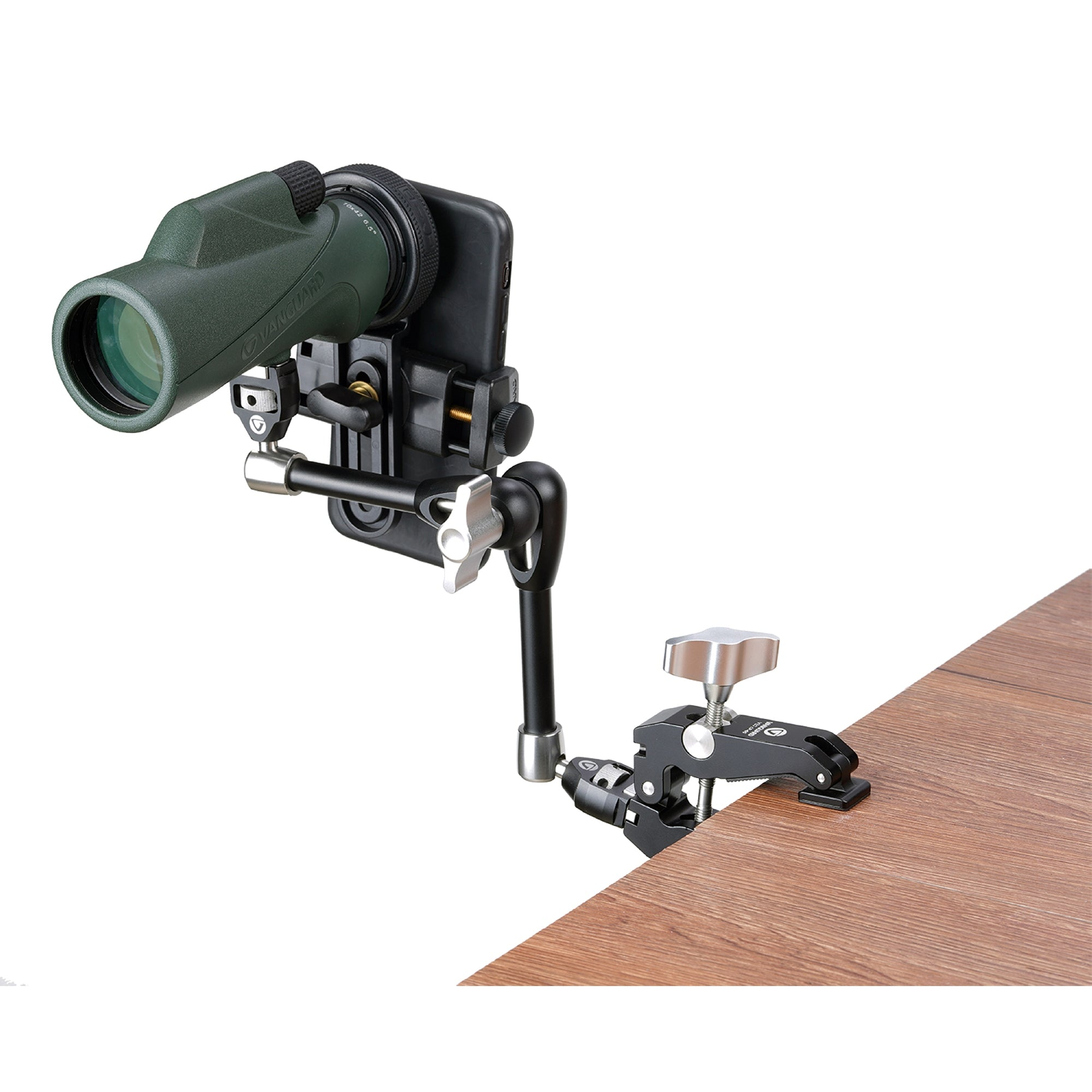 Un telescopio terrestre verde con soporte para teléfono sujeto a una mesa de madera.