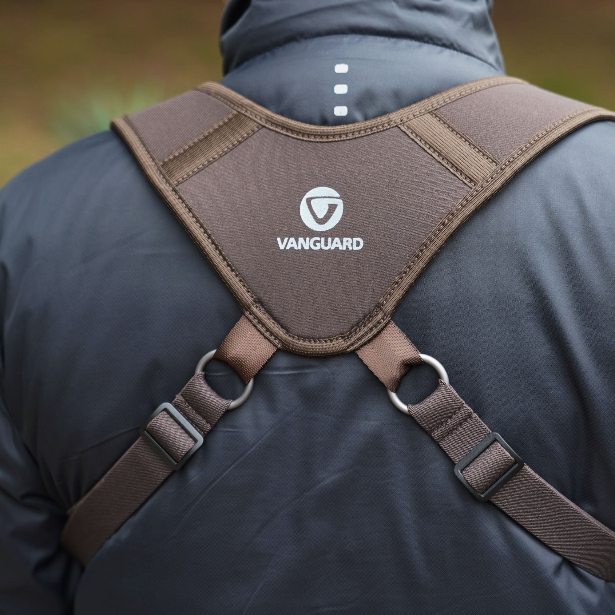 Una persona lleva un arnés marrón con el logo de Vanguard sobre una chaqueta oscura.