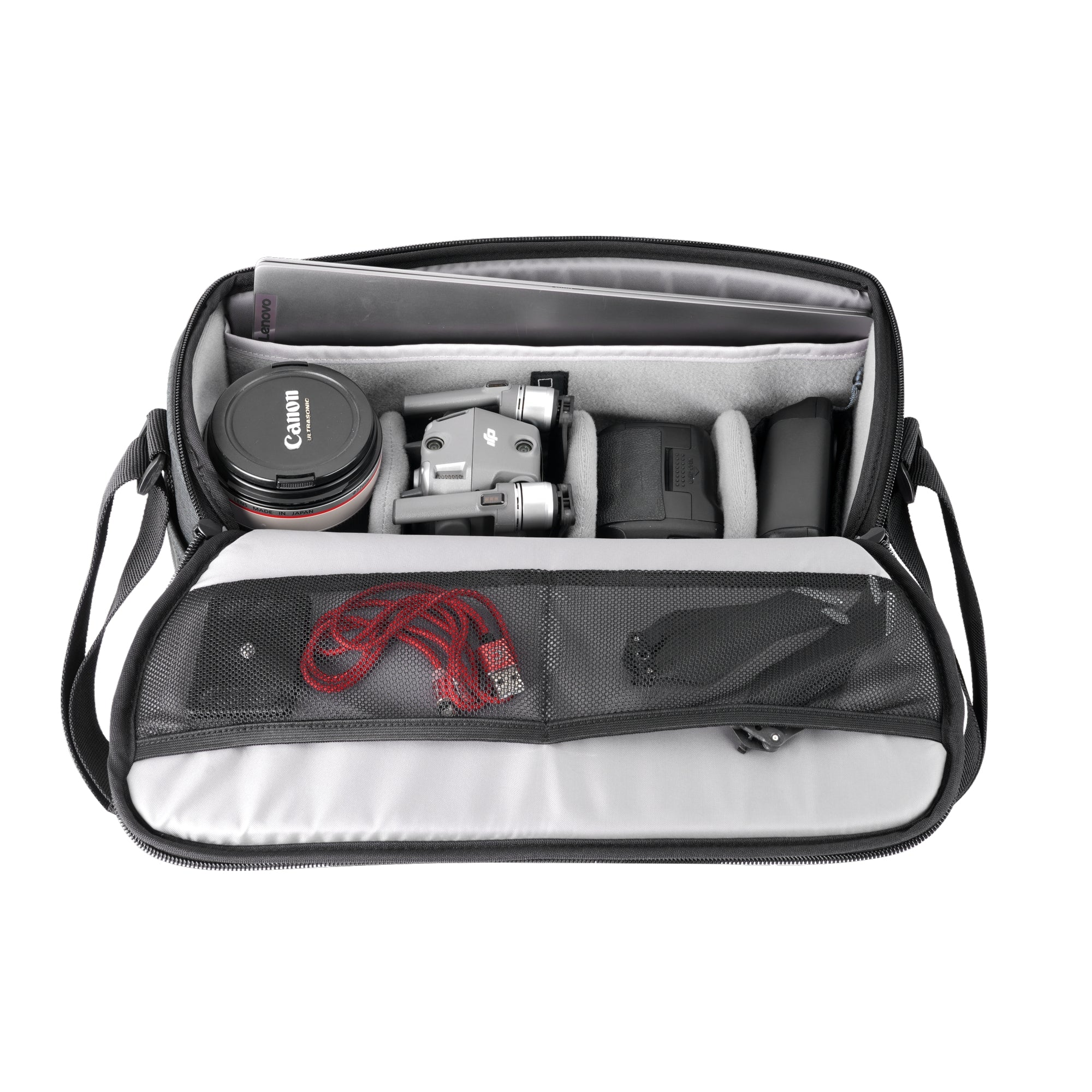 Una bolsa de cámara abierta con laptop, dron, tapa de lente y cables.