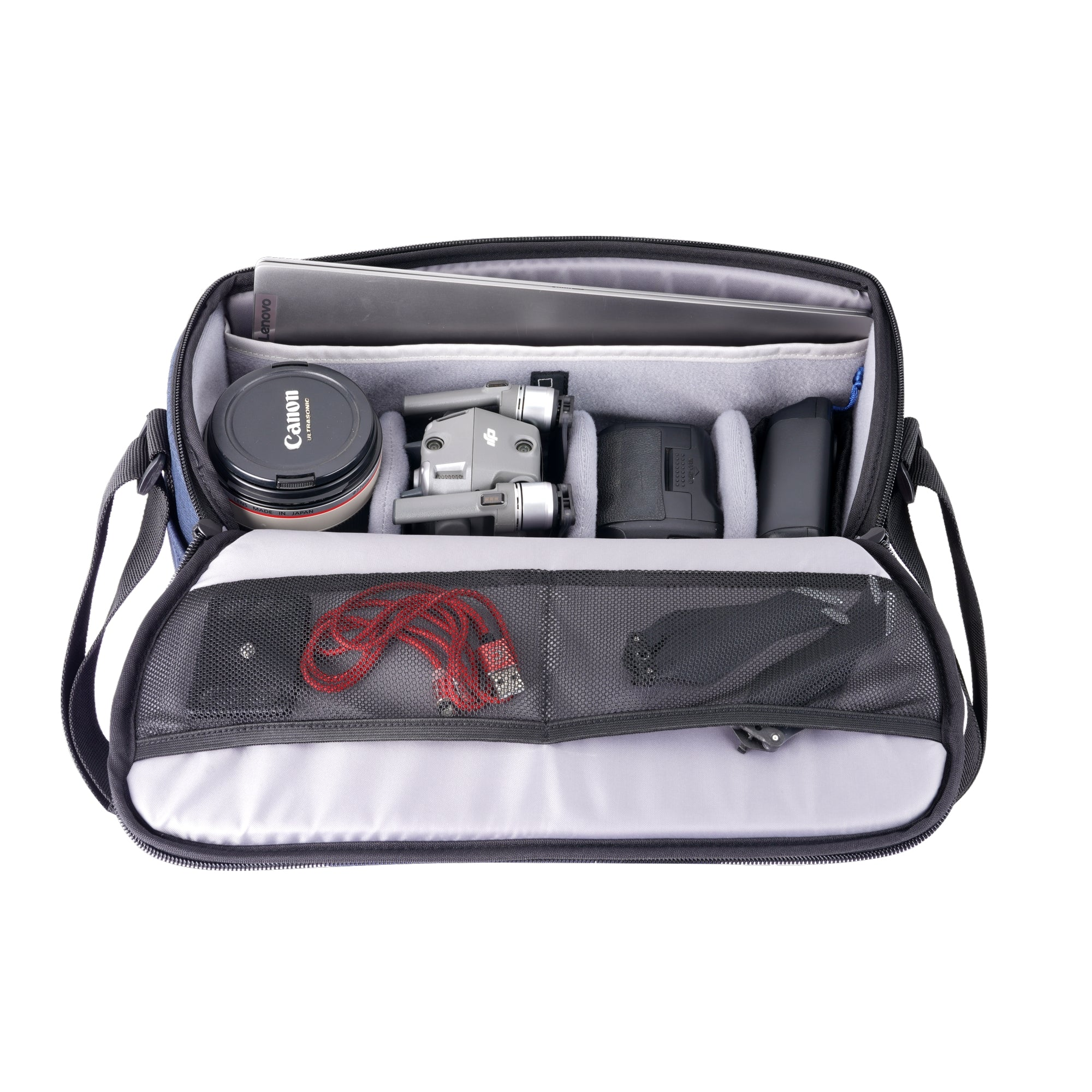 Una bolsa abierta con portátil, dron, lente de cámara y accesorios dentro.