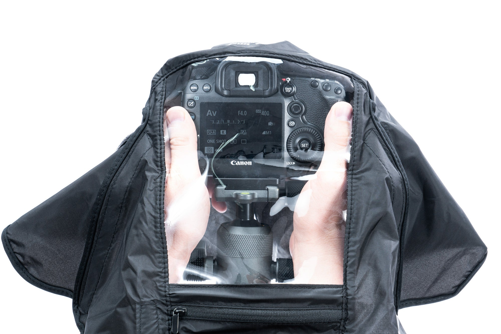 Manos operan una cámara Canon bajo una cubierta protectora negra.