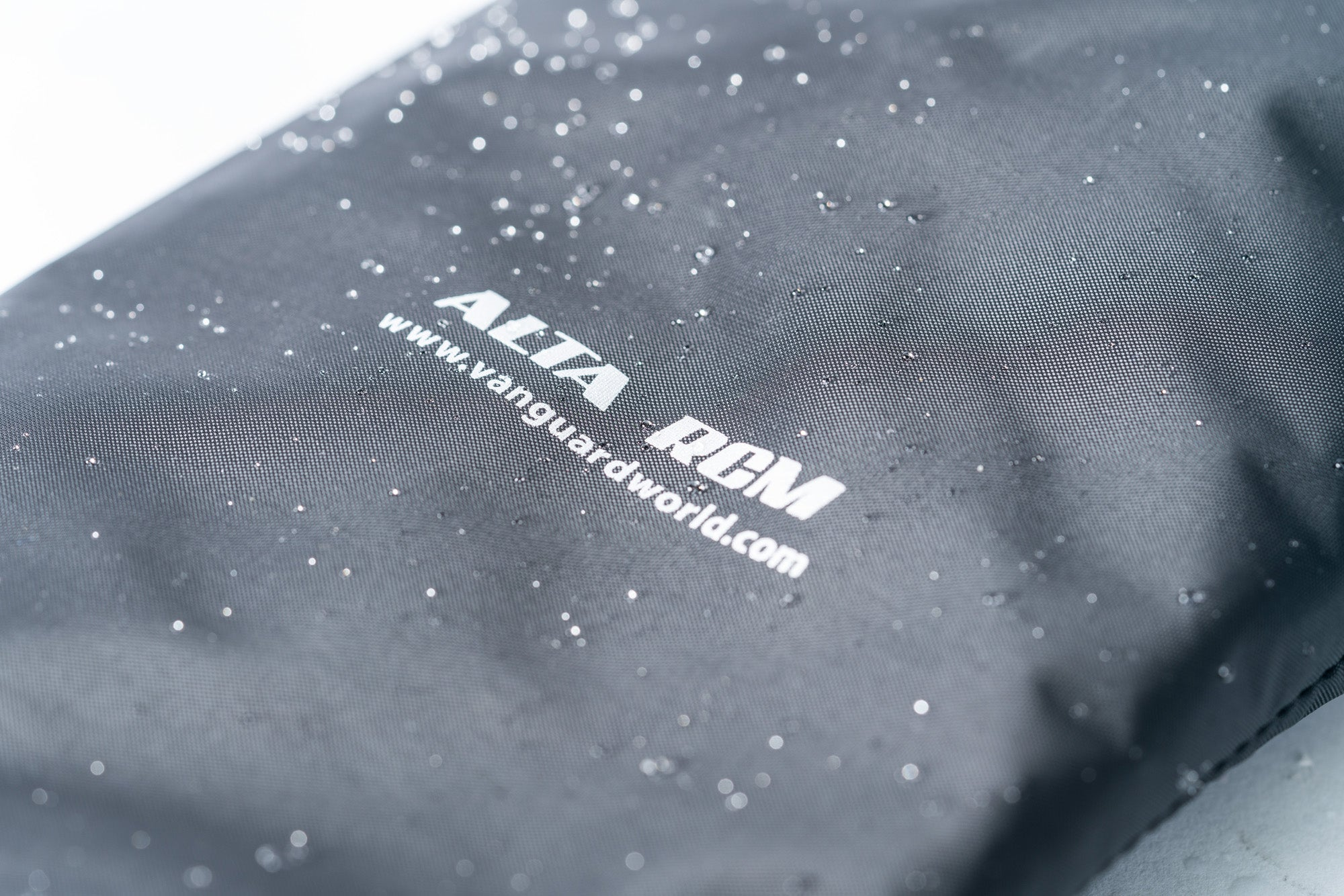 Bolsa de tela gris con gotas de agua y logo 'ALTA RGM'.