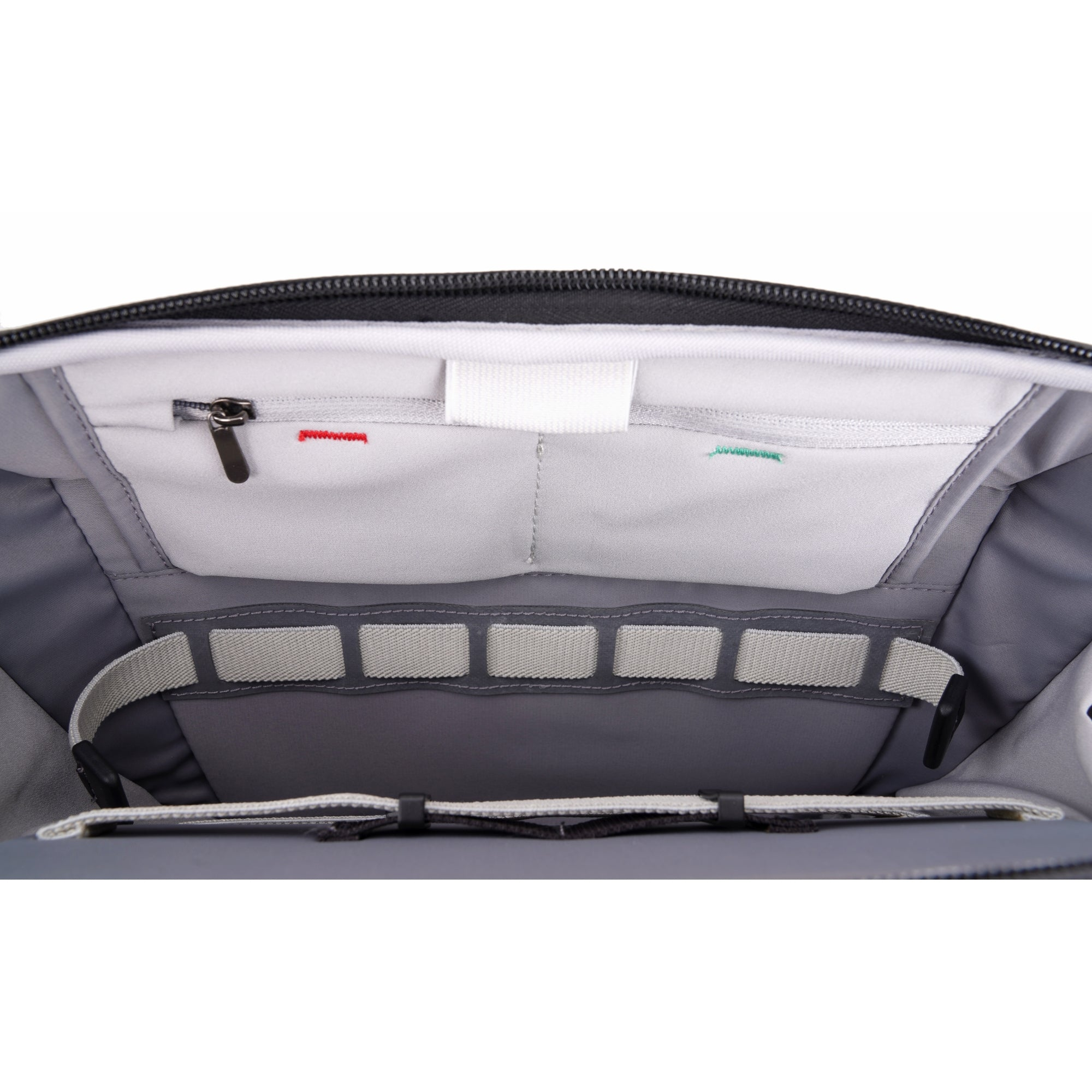 Interior de una bolsa con compartimentos y cremallera. Telas grises y blancas.