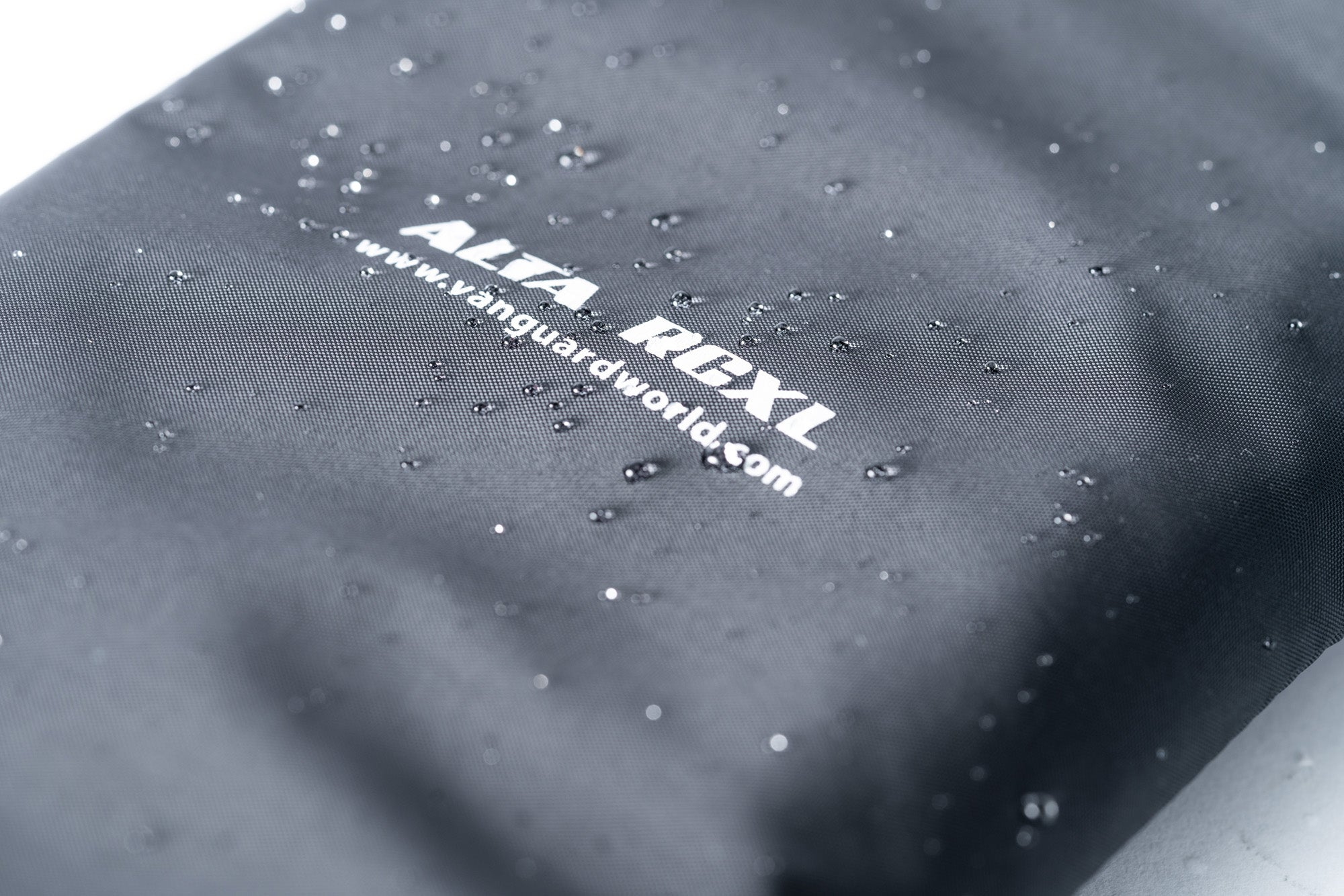 Textil gris con gotas de agua y logo blanco. Toma cercana.