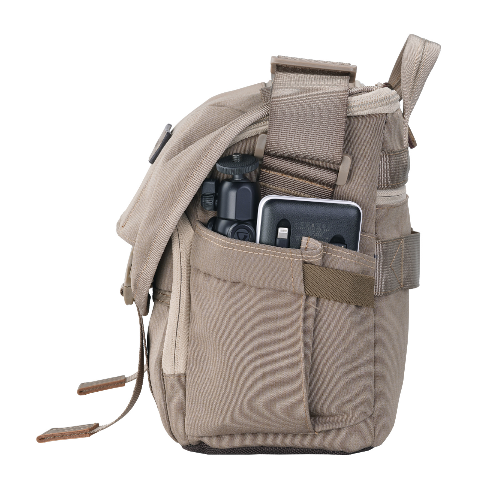 Una bandolera beige con un trípode pequeño y un smartphone en un bolsillo exterior.