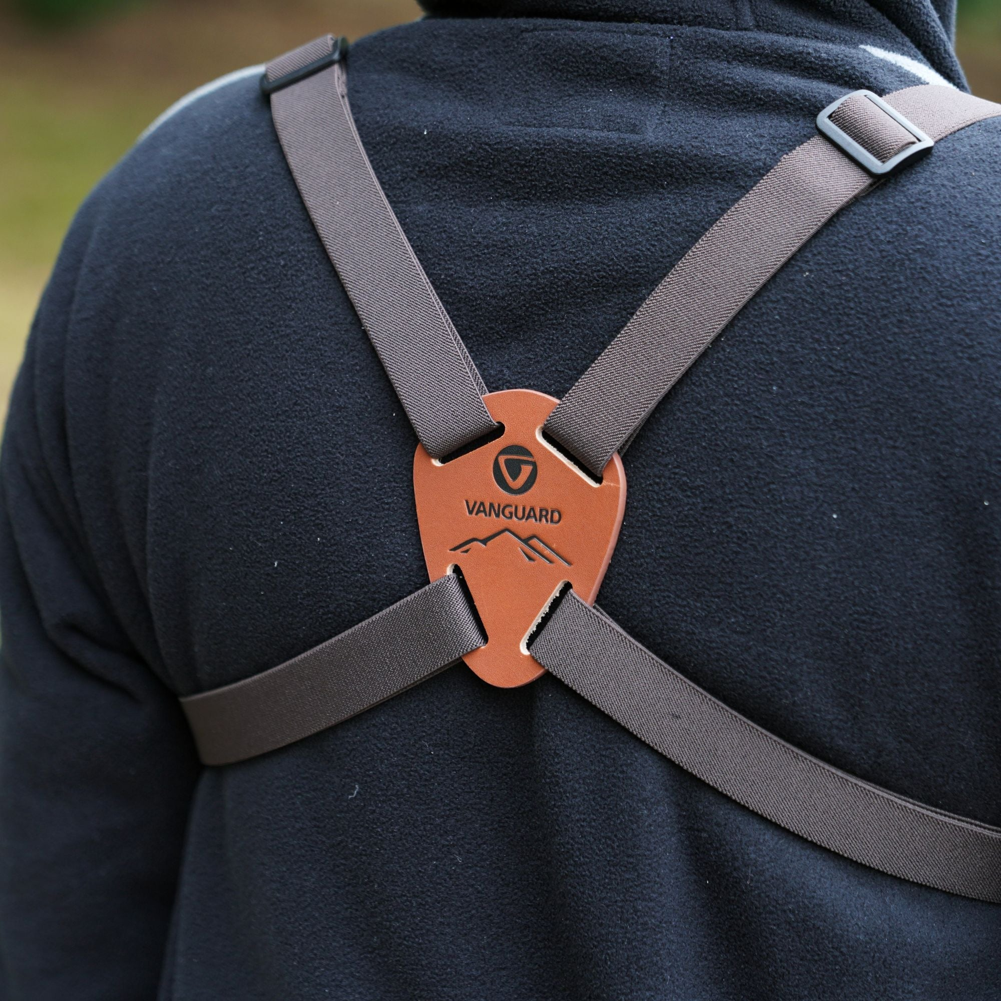 Peto de cuero marrón con diseño de montaña sobre sudadera negra con capucha.