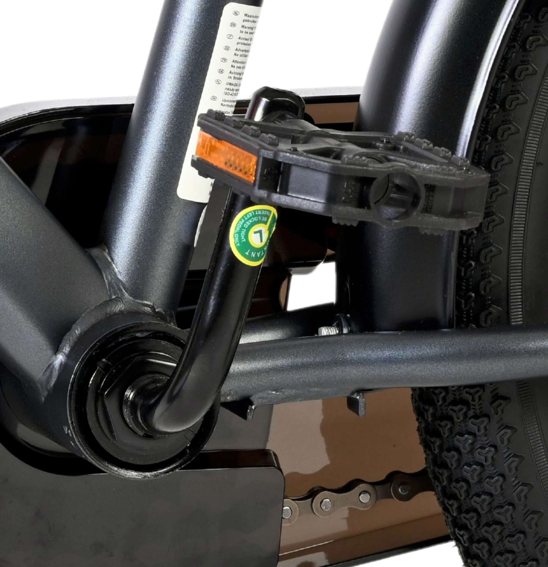 Nahaufnahme eines Fahrradpedals, Kette und Rad mit Warnhinweisen.