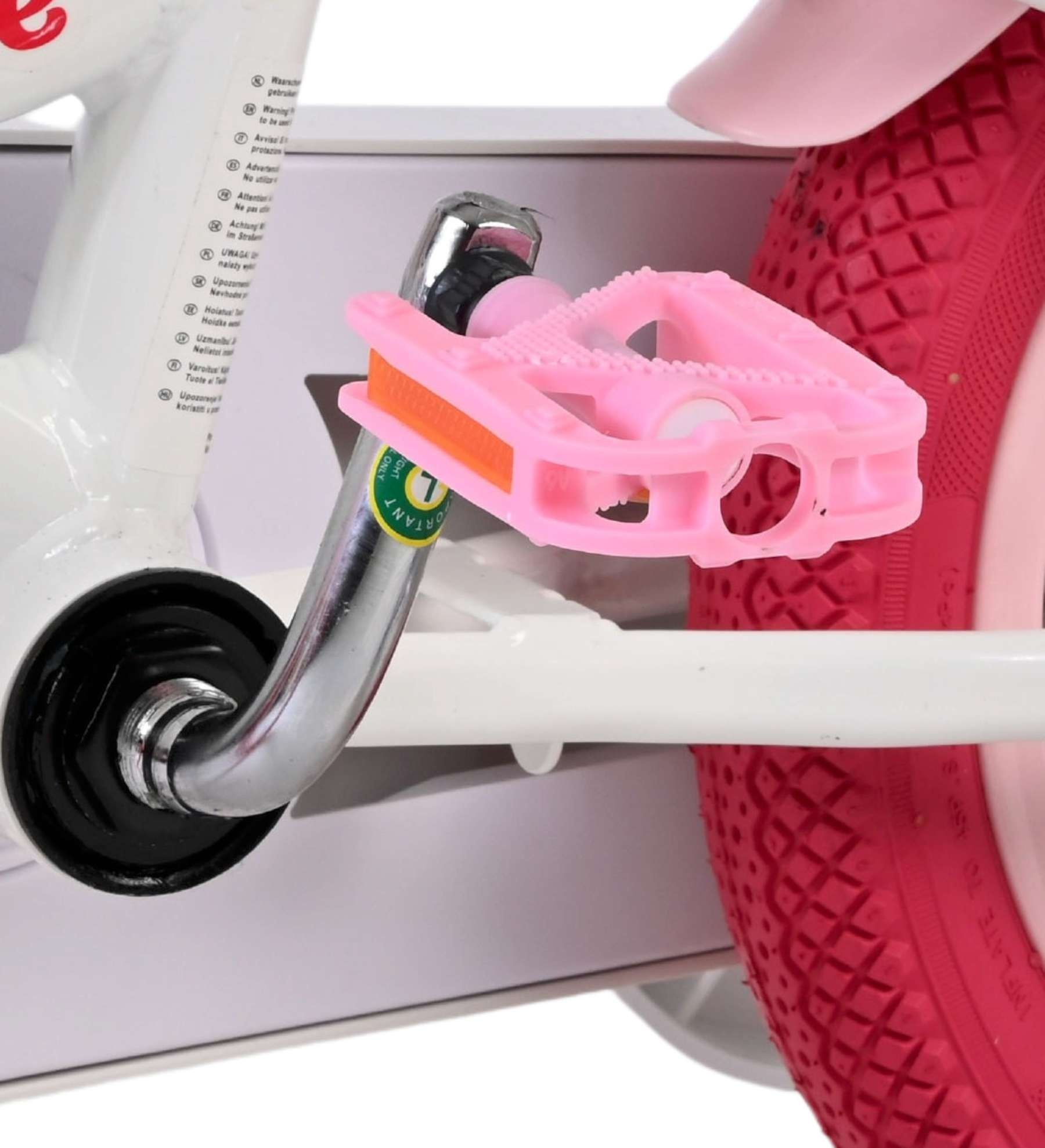 Ein pinker Fahrradpedal mit orangem Reflektor neben einem roten Rad.