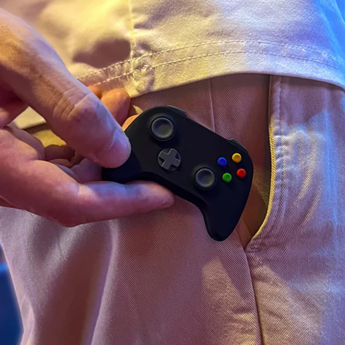 Una mano tiene un piccolo controller di gioco nero vicino a una tasca.
