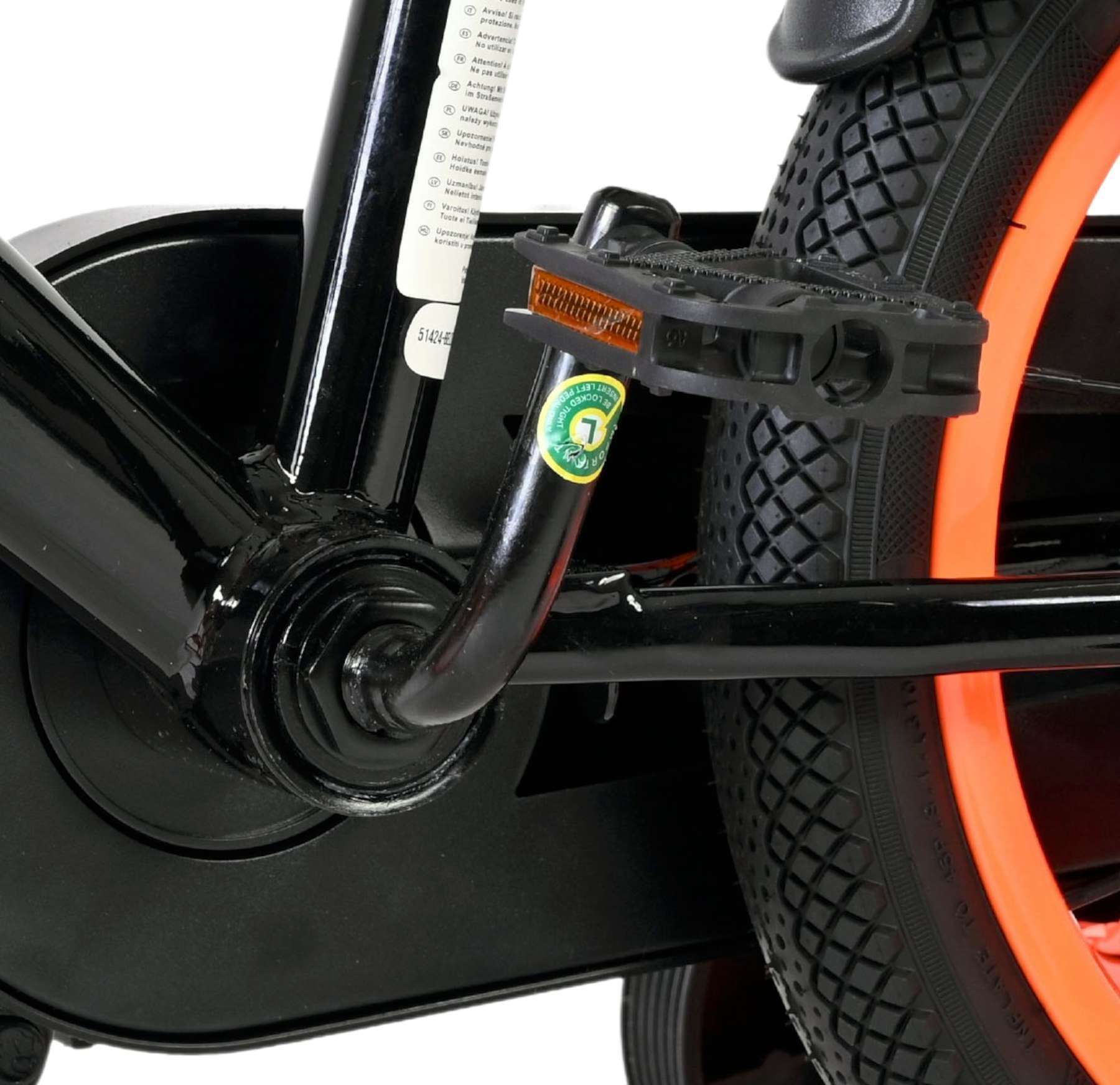 Nahaufnahme eines Fahrradpedals und eines orangen Rads mit schwarzem Reifen.