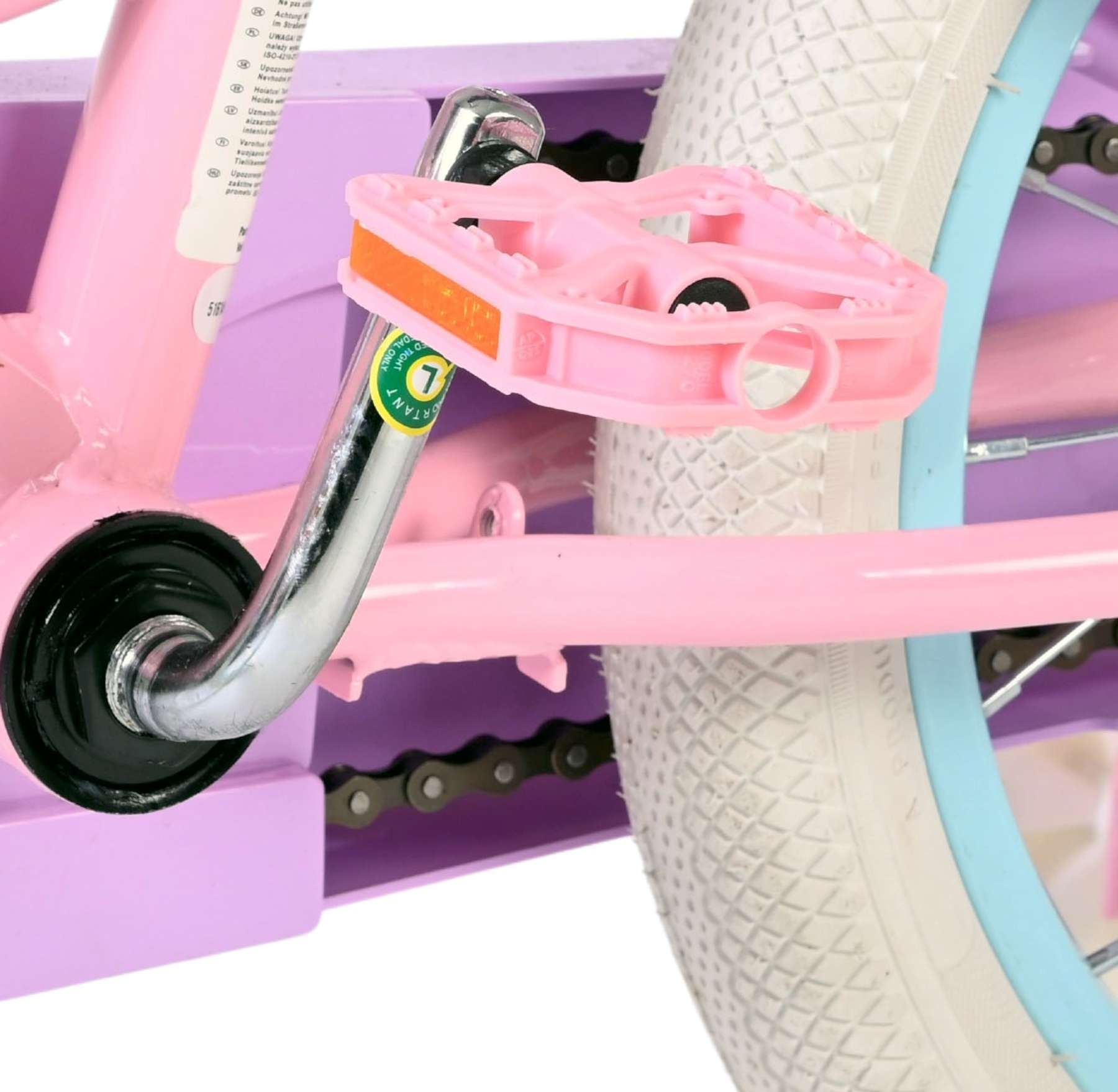 Nahaufnahme des pinken Pedals und Rades eines Kinderfahrrads mit lila Rahmen.