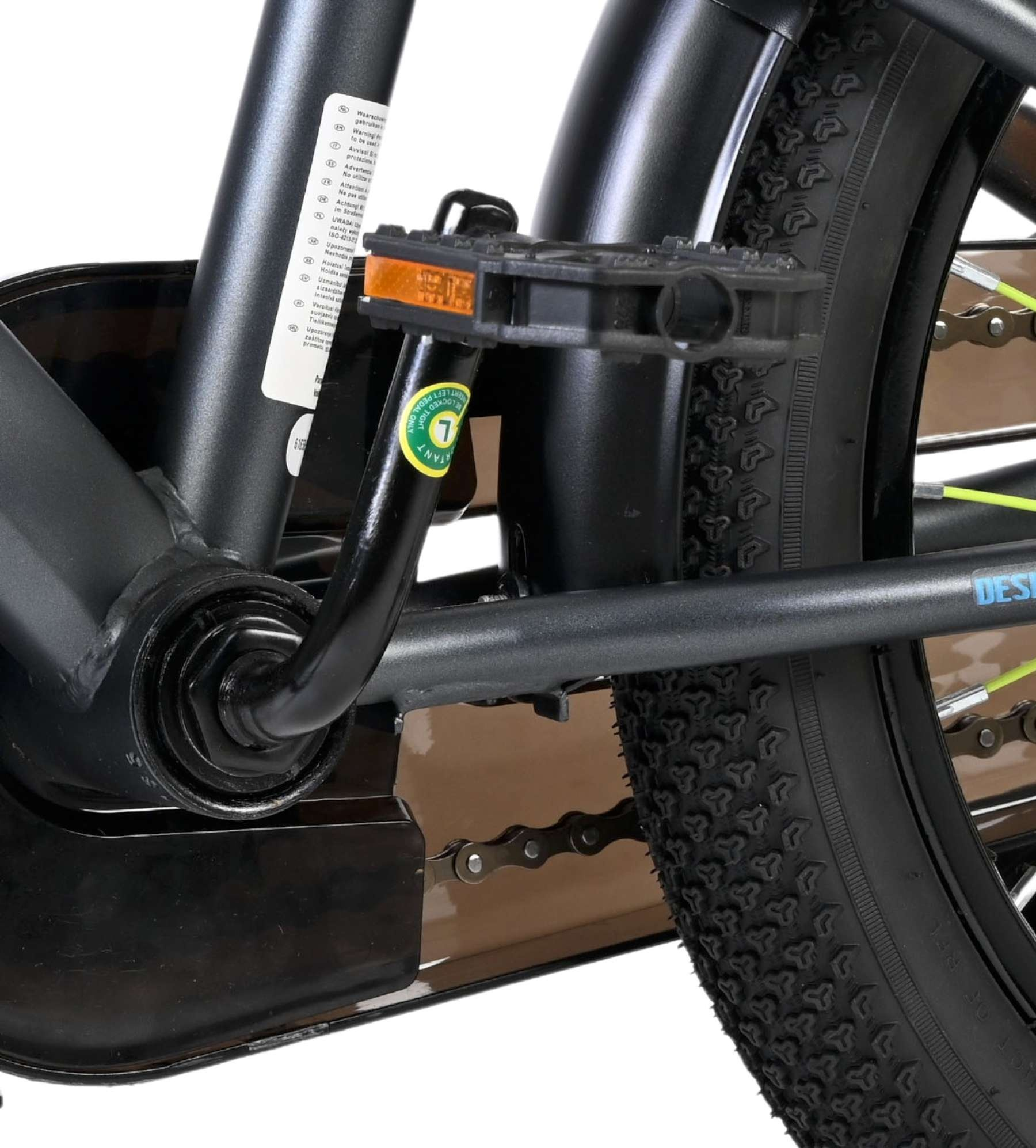 Nahaufnahme der Fahrradkette, des Pedals und des Reifens mit Warnhinweisen.