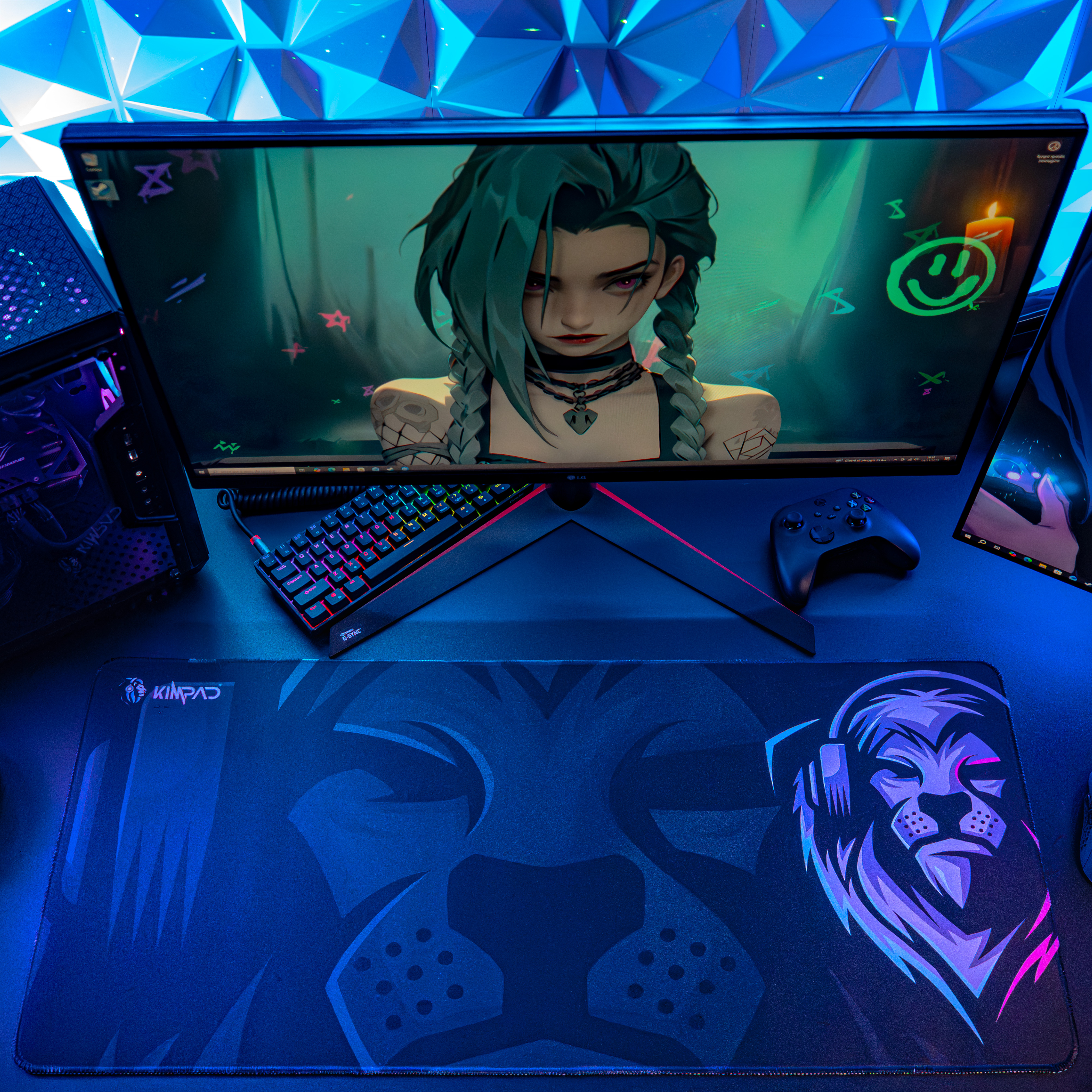 Una postazione da gaming con monitor, tastiera, tappetino e controller, illuminata in blu.