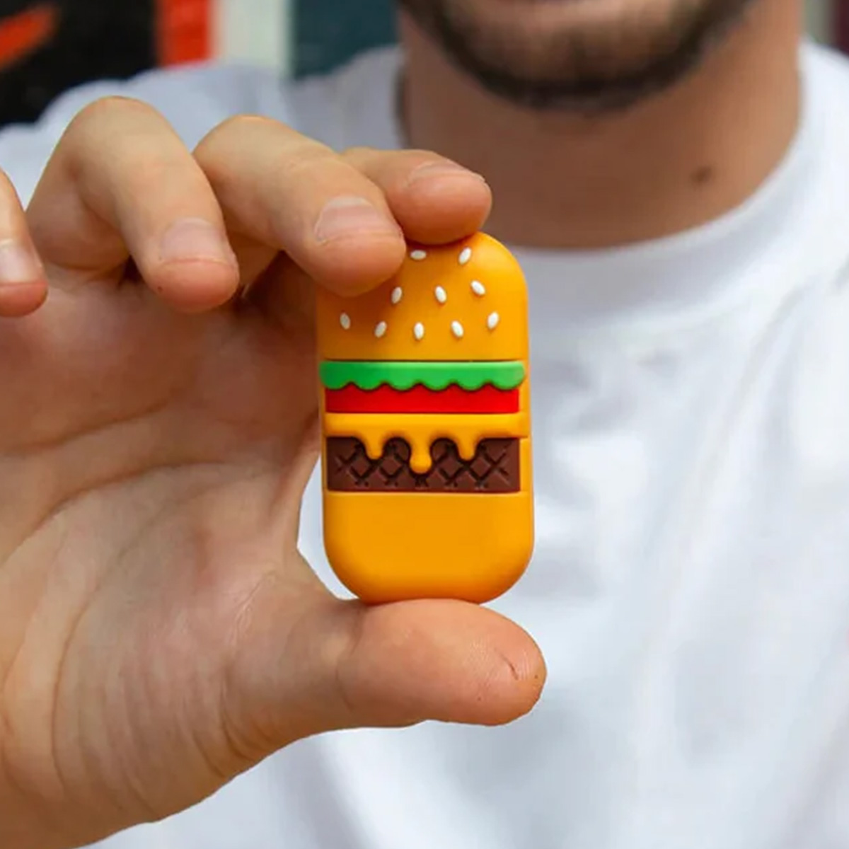 Un uomo tiene una chiavetta USB colorata a forma di hamburger.