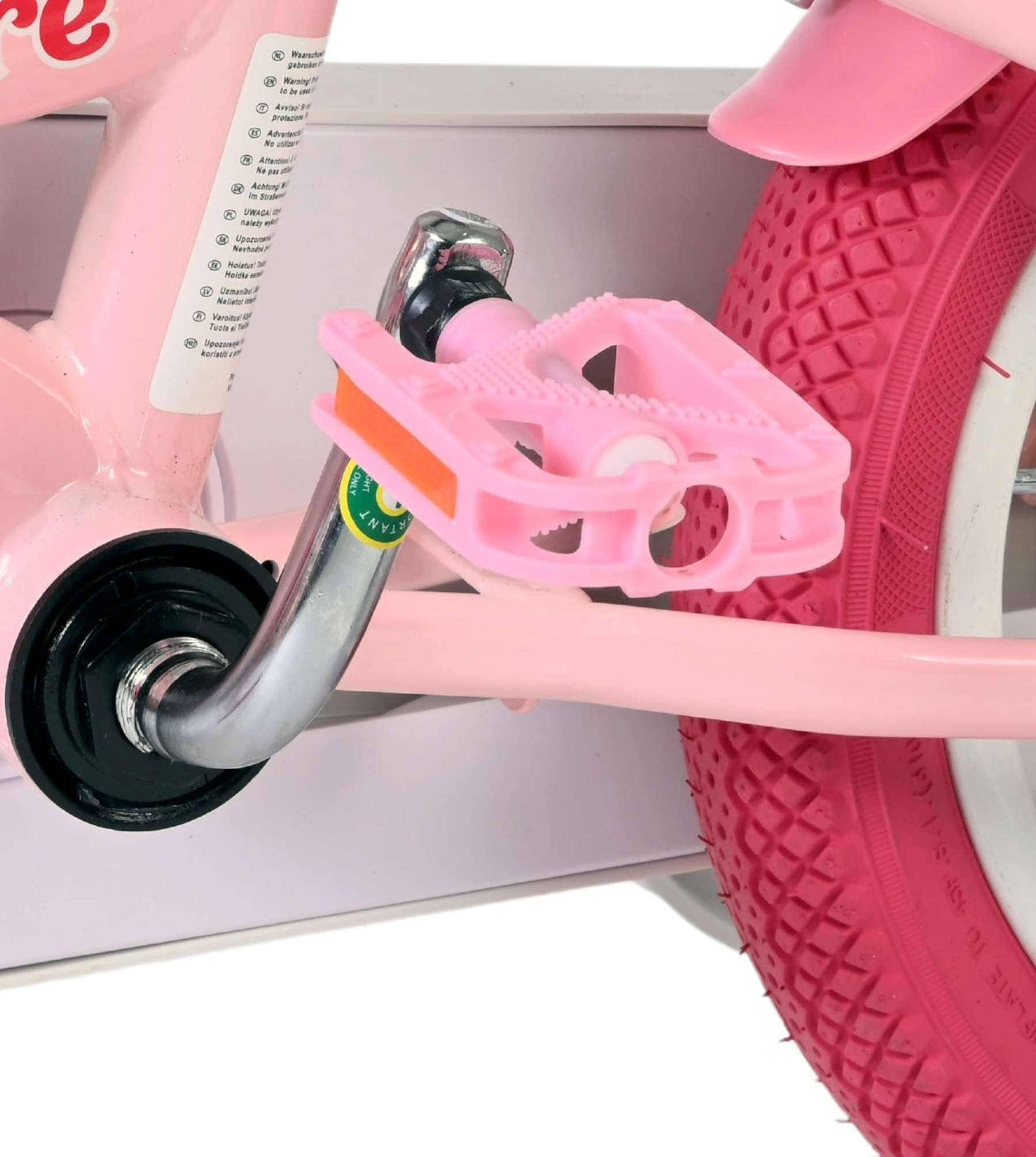 Nahaufnahme eines rosa Fahrradpedals und Rads mit Warnhinweisen auf dem Rahmen.
