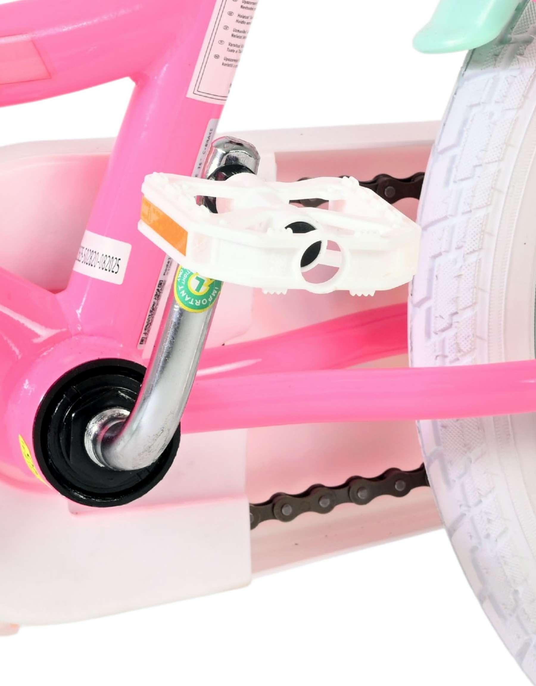 Nahaufnahme einer rosa Kinderfahrradkette, Pedale und weißem Reifen.