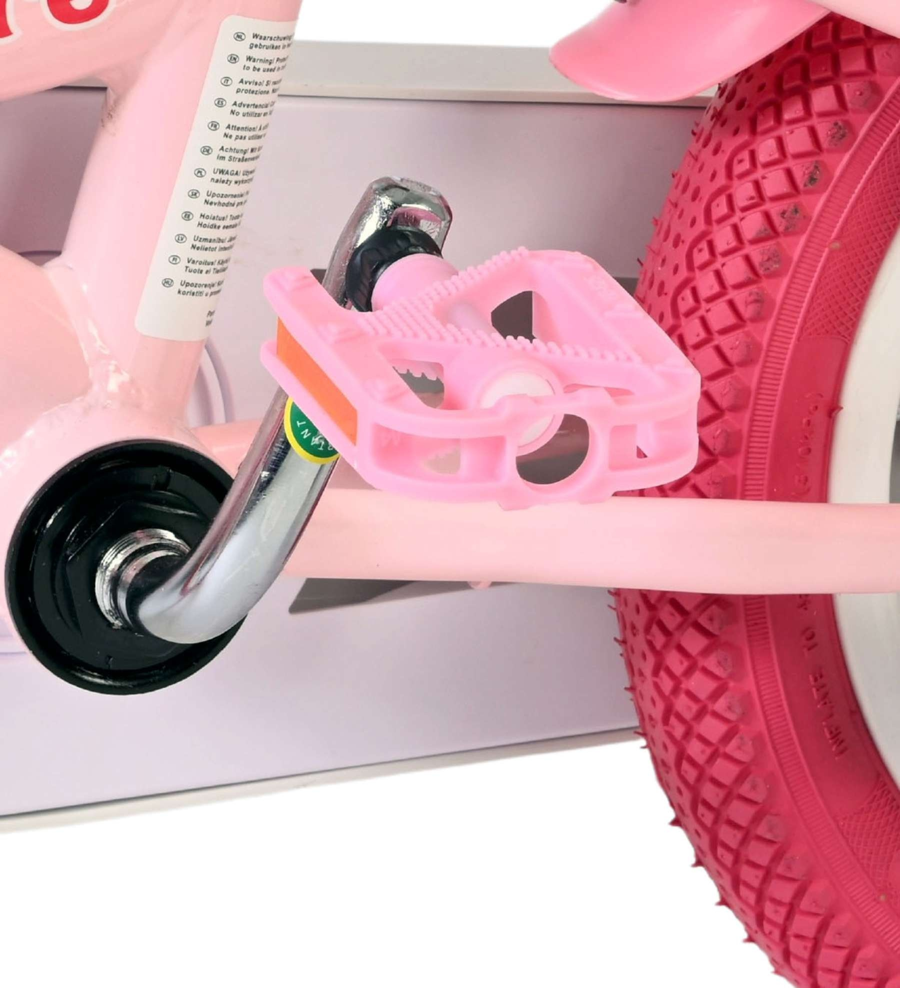 Nahaufnahme eines pinken Fahrradpedals und Rads mit Warnhinweisen.
