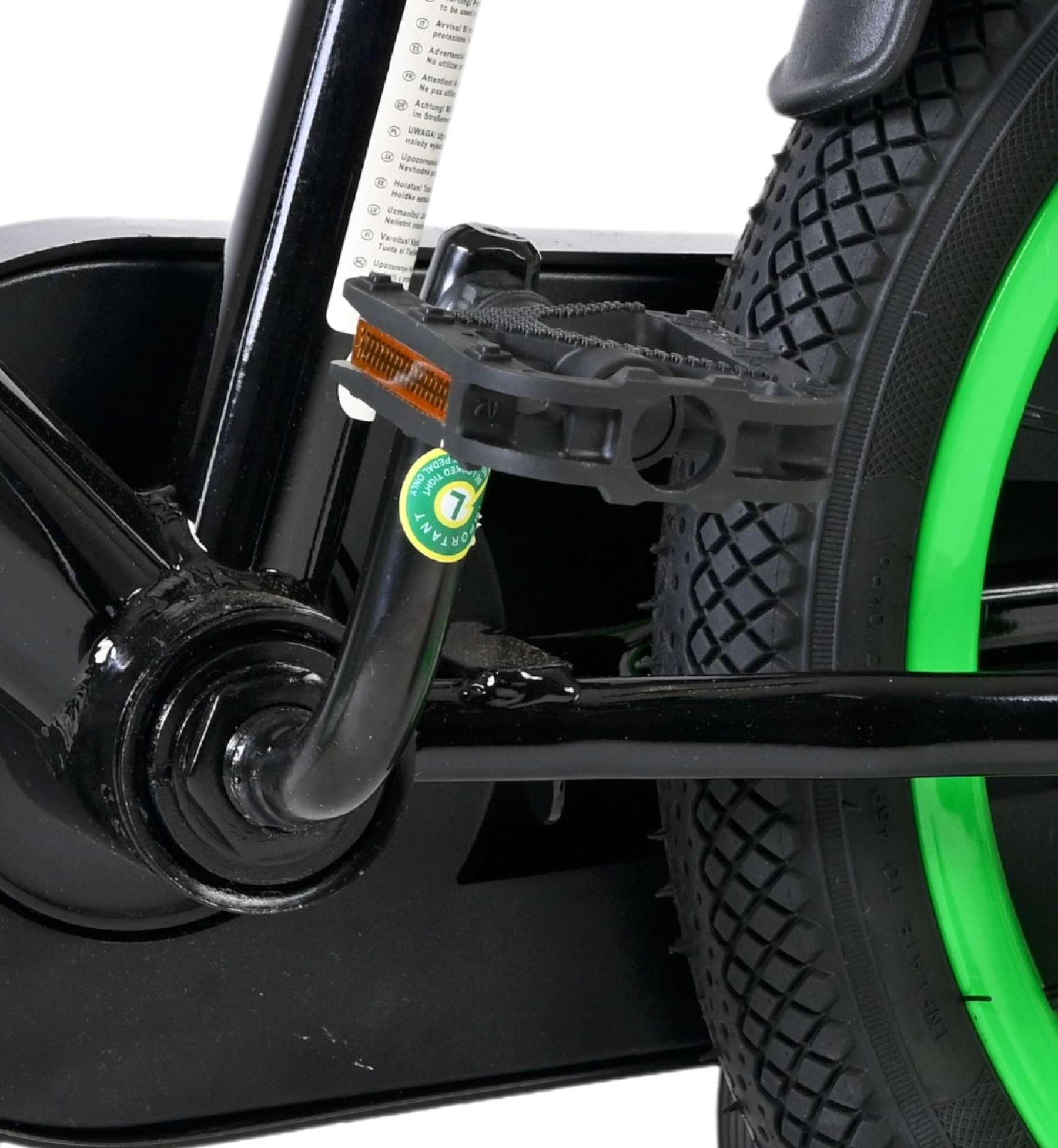 Nahaufnahme eines Fahrradpedals mit Kette und grünem Rad.
